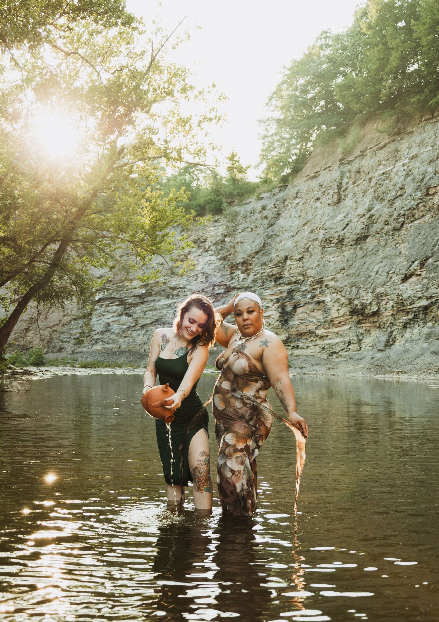 People enjoy wading in a scenic quarry pool surrounded by tall limestone cliffs on a bright summer day.