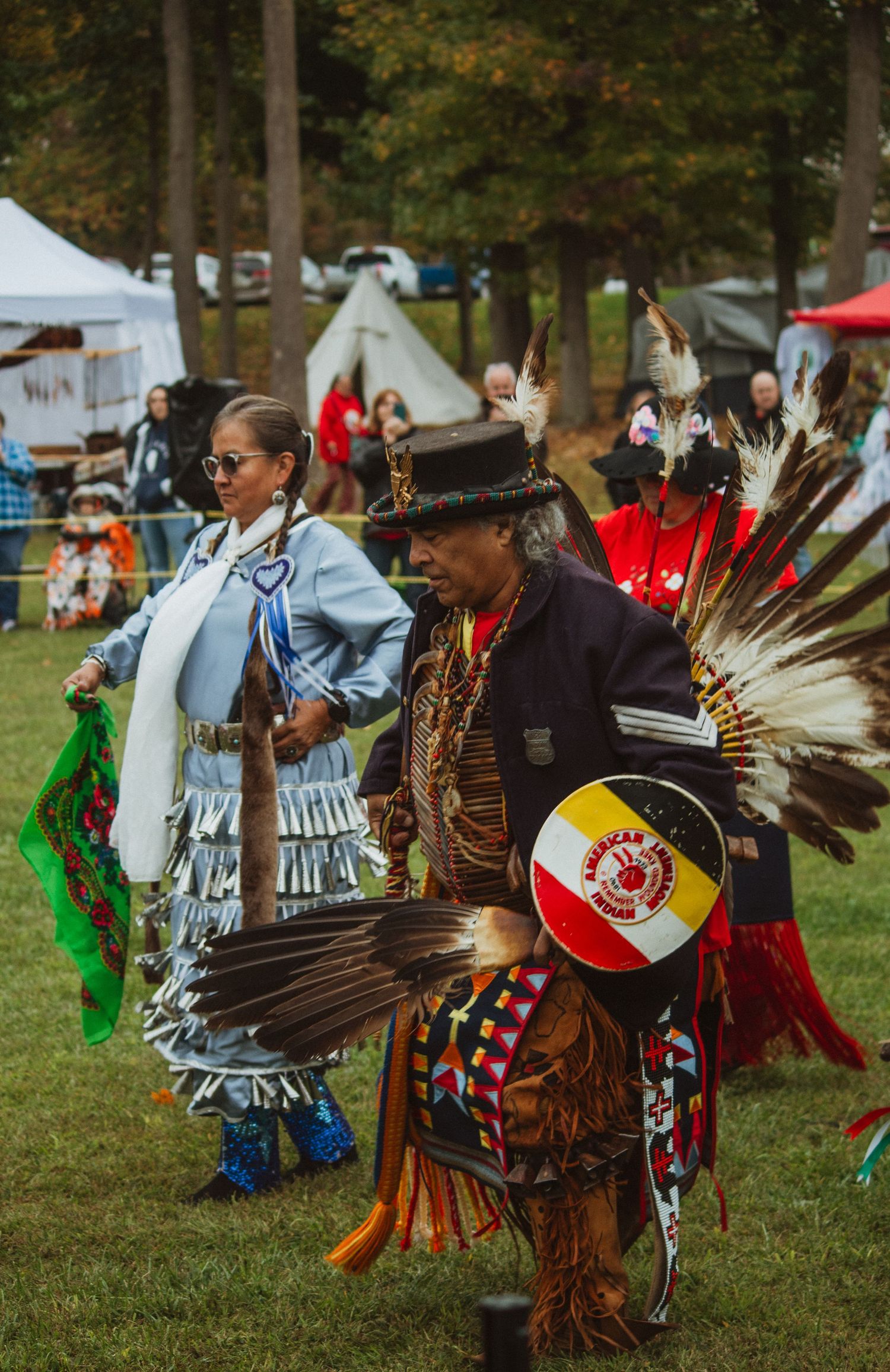 Traditional dancers in ornate regalia with feathers and beadwork perform at a Native American cultural festival.