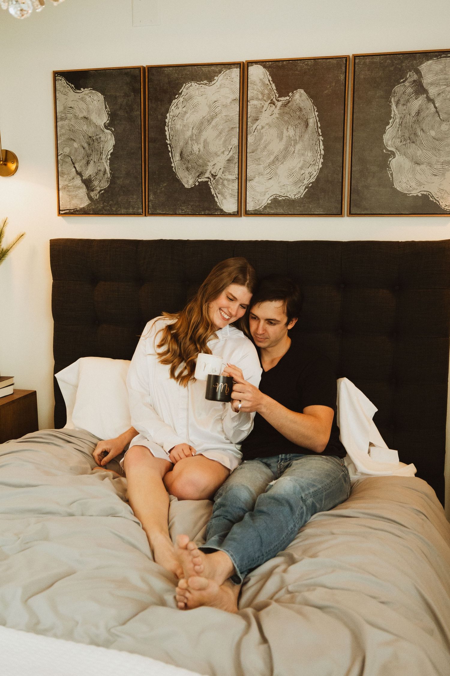 Romantic morning in bed with coffee mugs and modern monochrome artwork above headboard.
