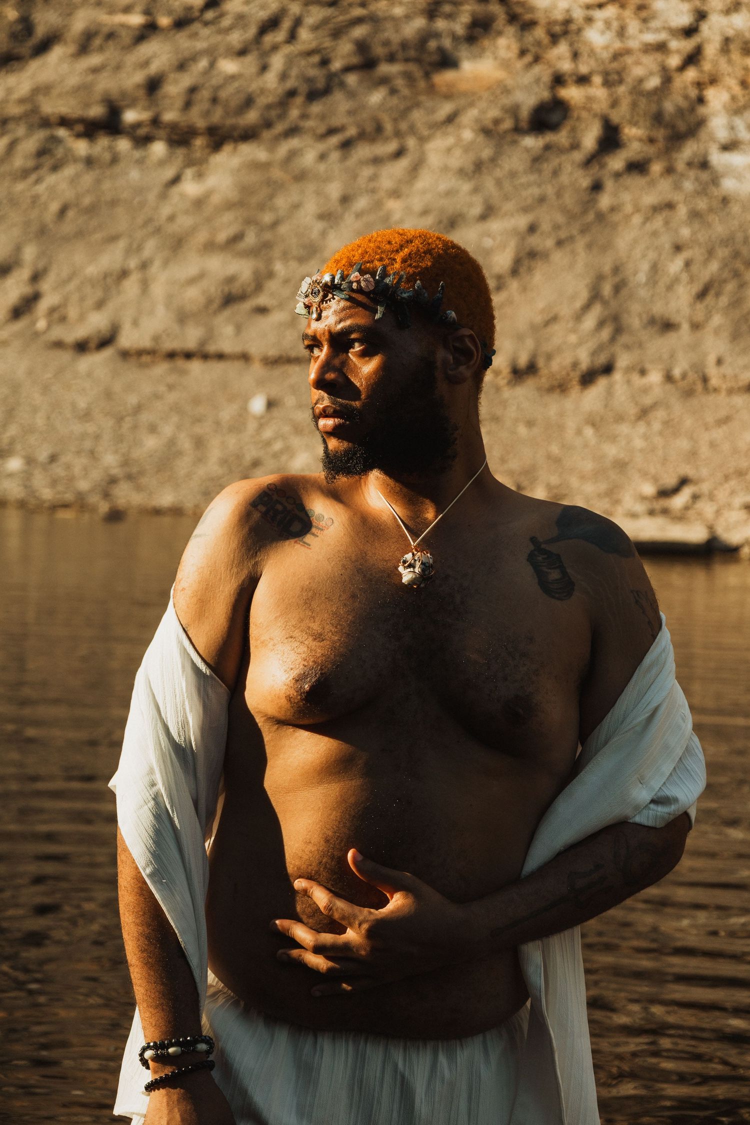 Artistic portraits captured in golden sunlight against a rocky waterfront backdrop.