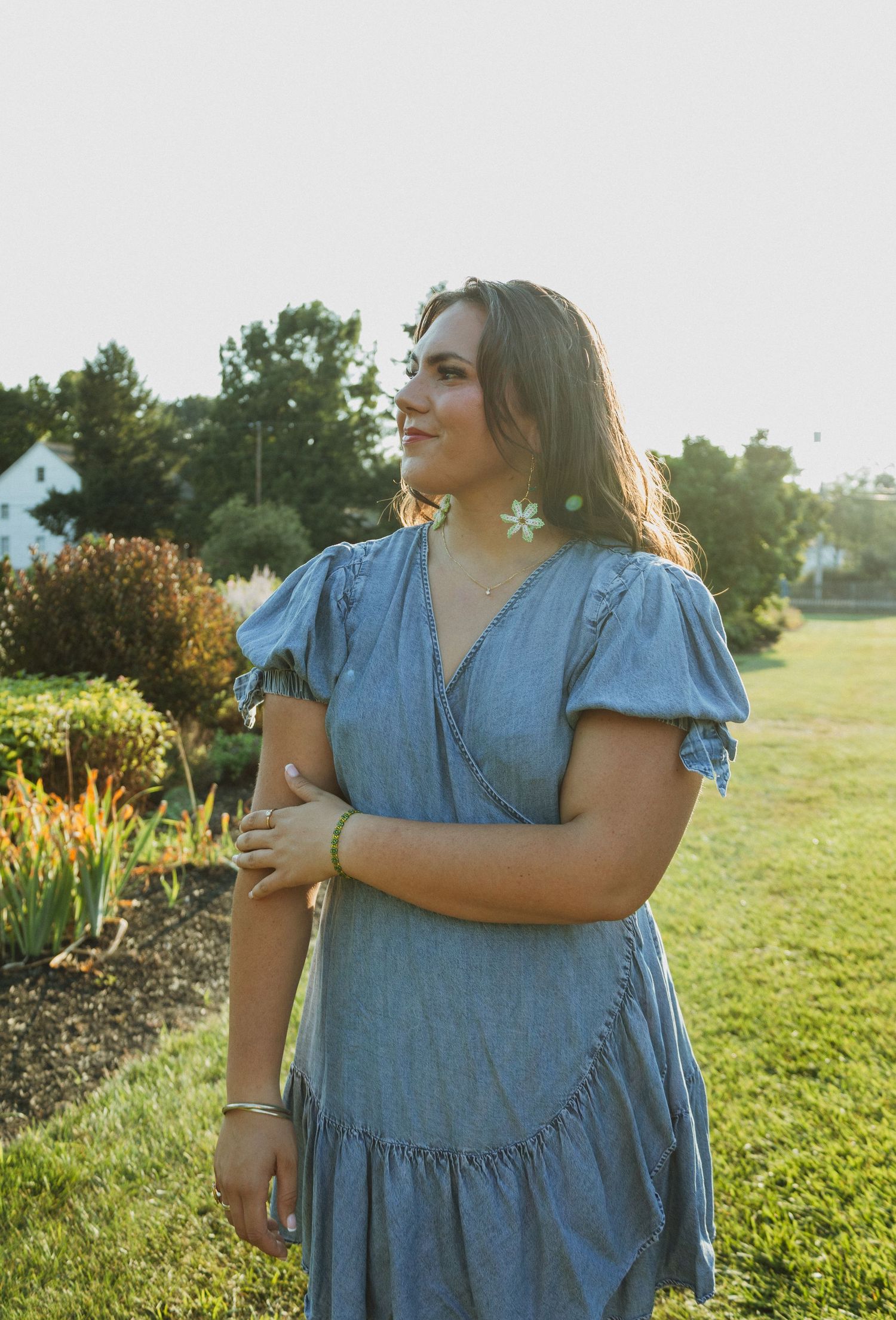 Someone in a flowing blue denim dress stands in a sunny field at golden hour, captured in multiple poses.