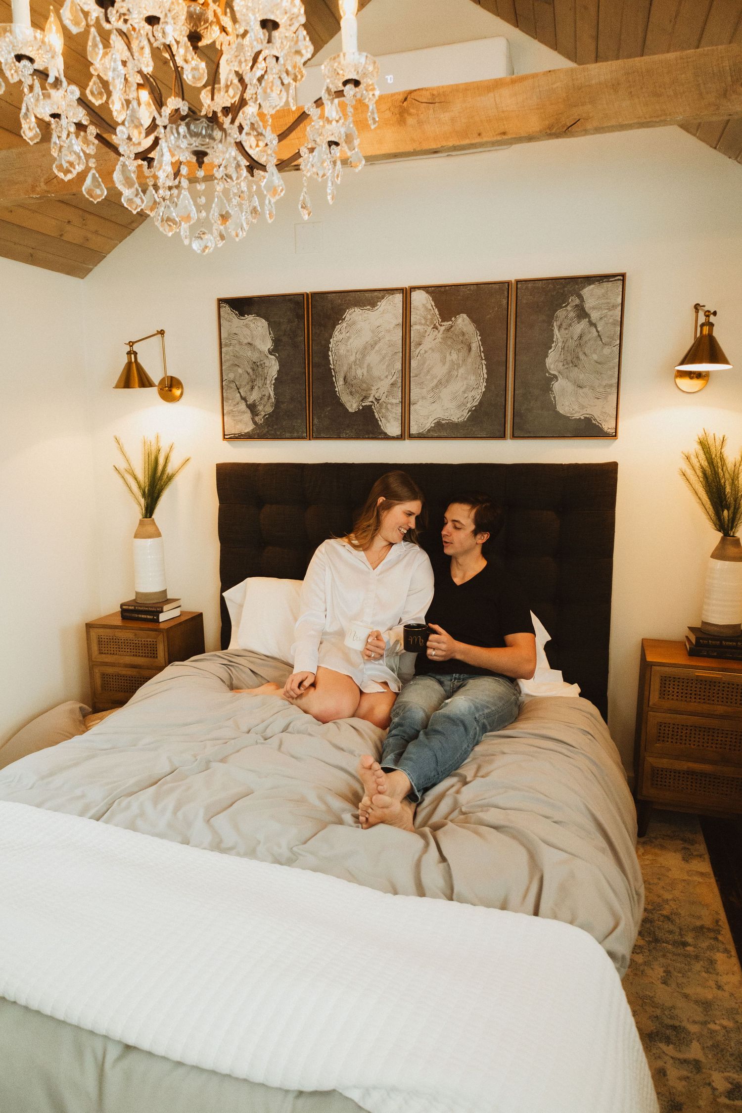 Modern bedroom with exposed wood beams, crystal chandelier and abstract wall panels.