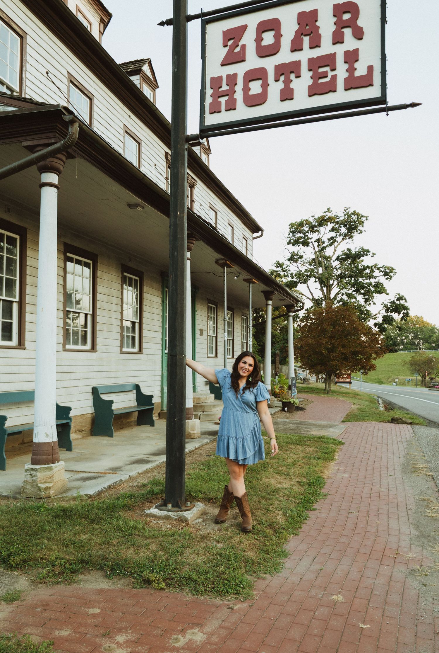 A sequence of photos showing a figure twirling in a blue dress along a brick walkway beside a historic hotel building.