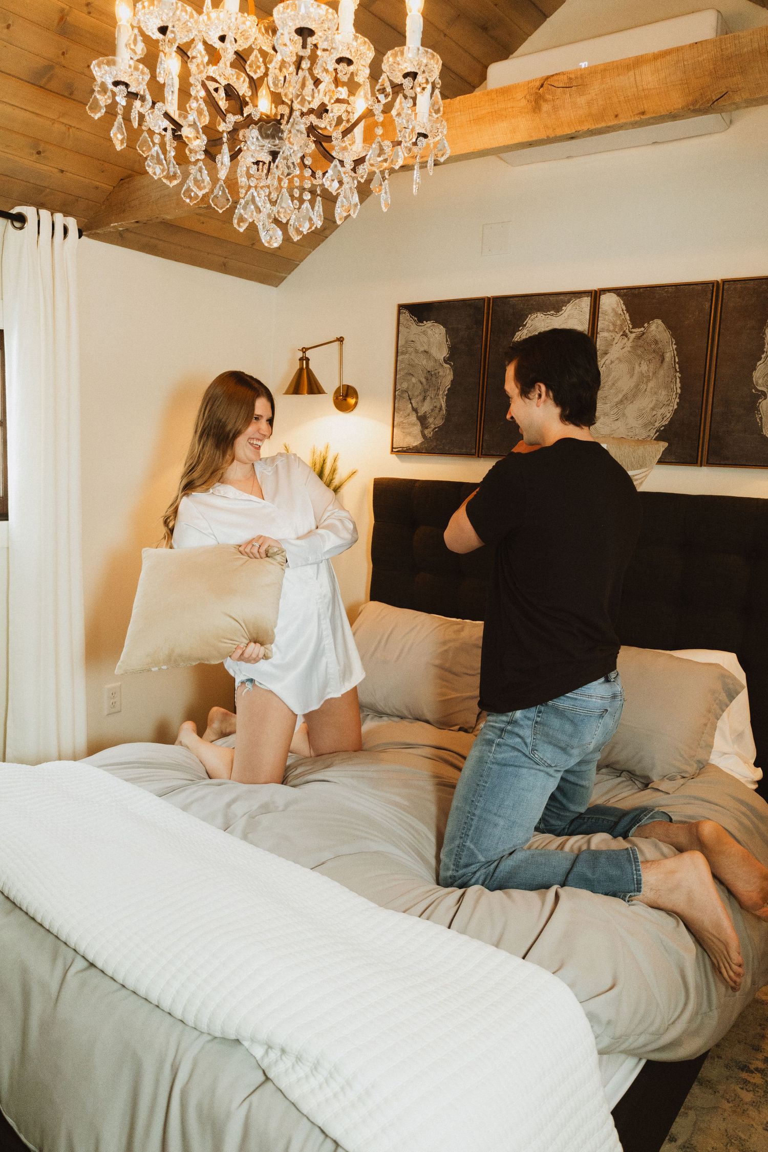 A casual scene in a rustic bedroom with elegant chandelier and neutral decor.