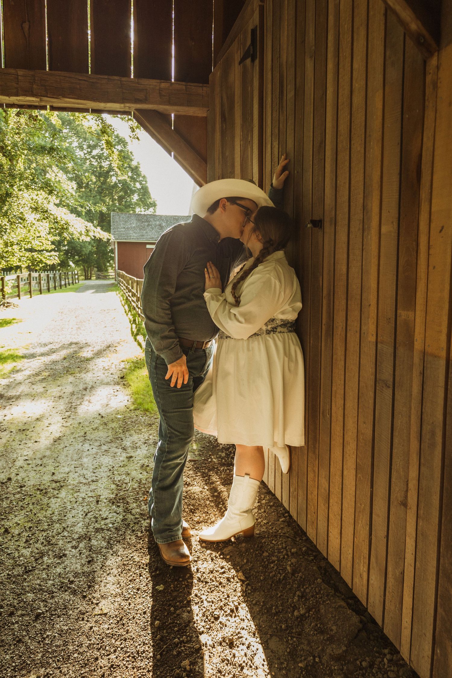 A tender moment shared between a couple leaning against a wooden barn wall.
