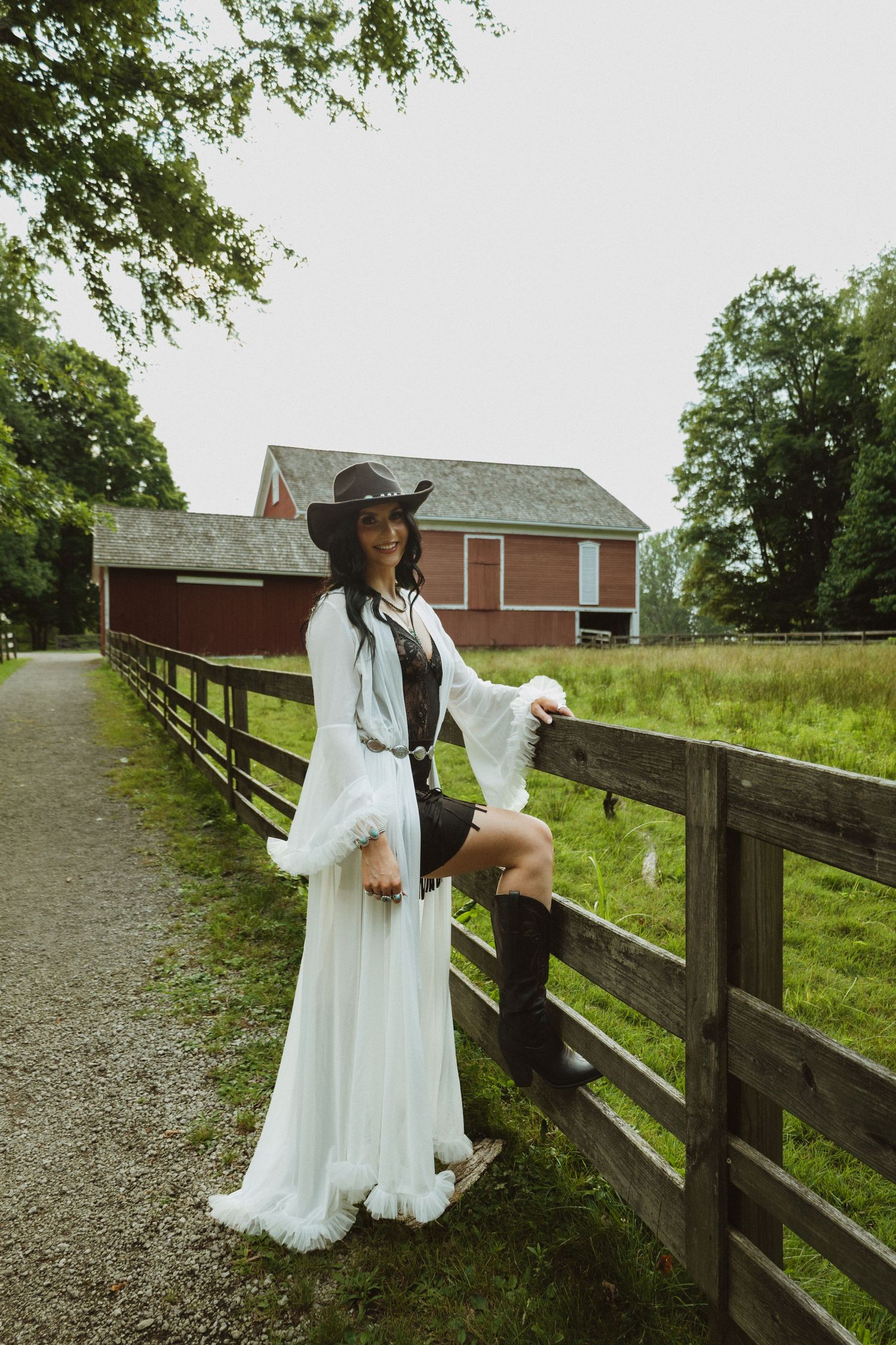 A series of photos showing someone in a white dress and wide-brimmed hat posing along a rustic wooden fence on a farm.