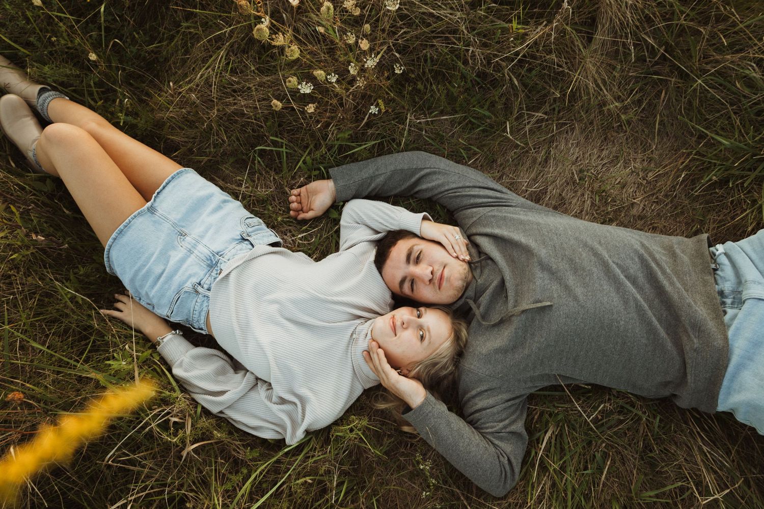 Pair laying head-to-head on grass during a warm sunset photoshoot.