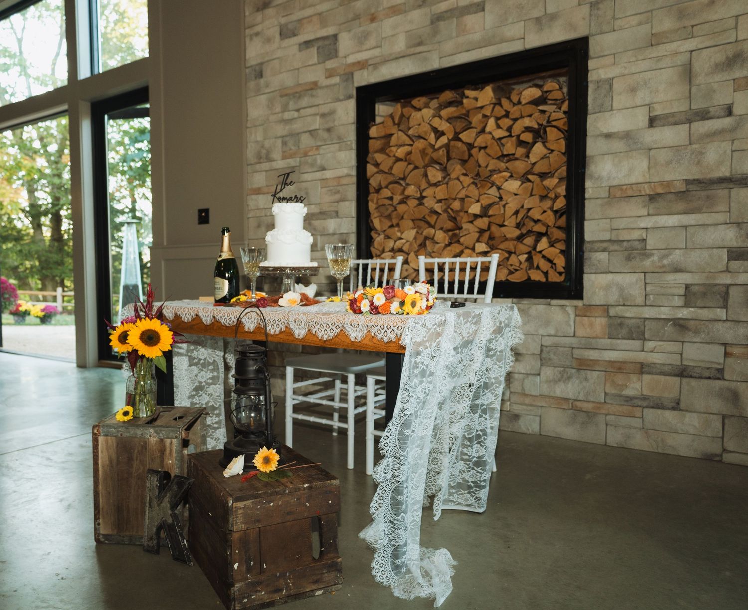 Modern reception venue with stone walls, firewood storage, and rustic autumn decorations.