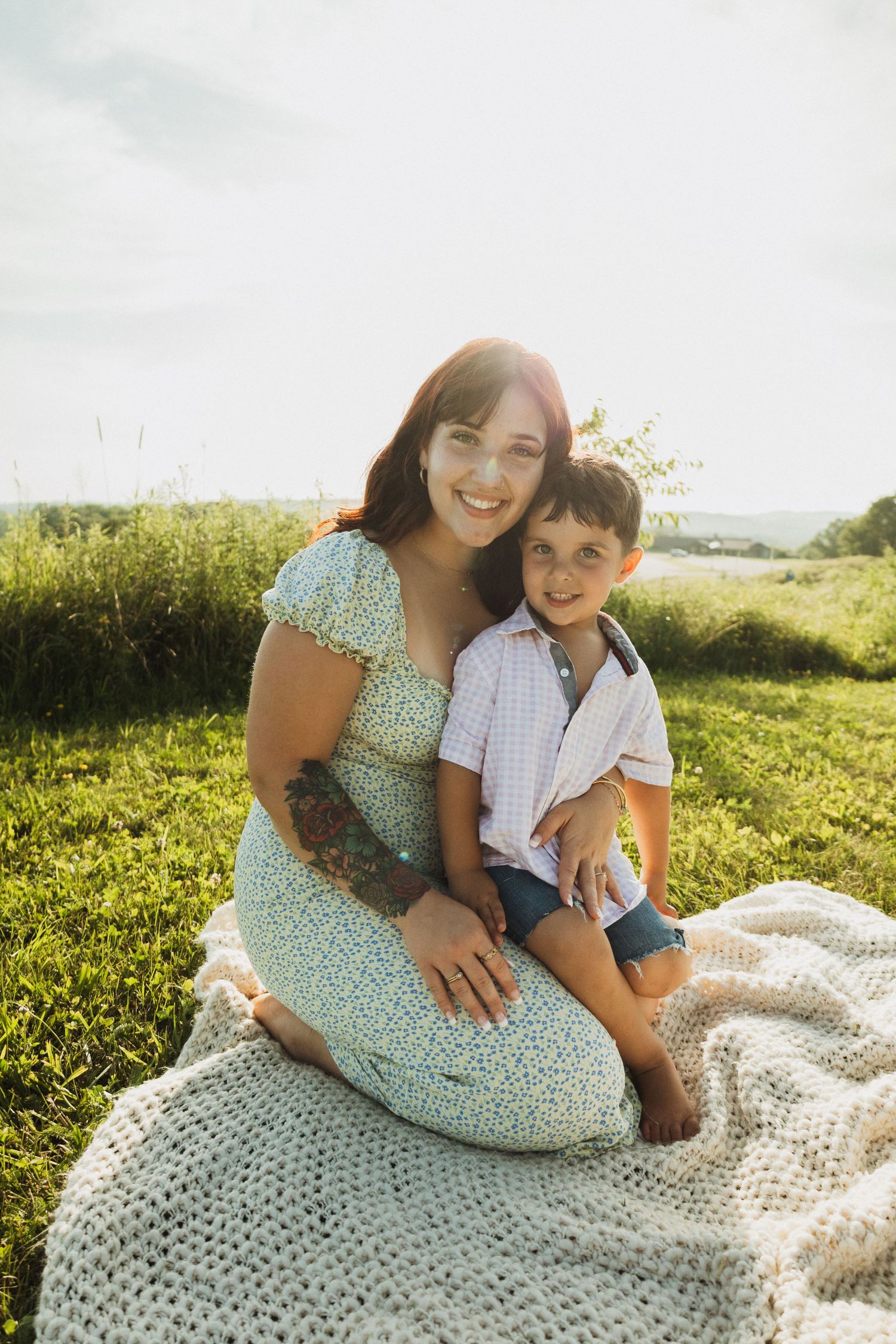 A tender moment captured on a knitted blanket in a sunny meadow during a family photoshoot.