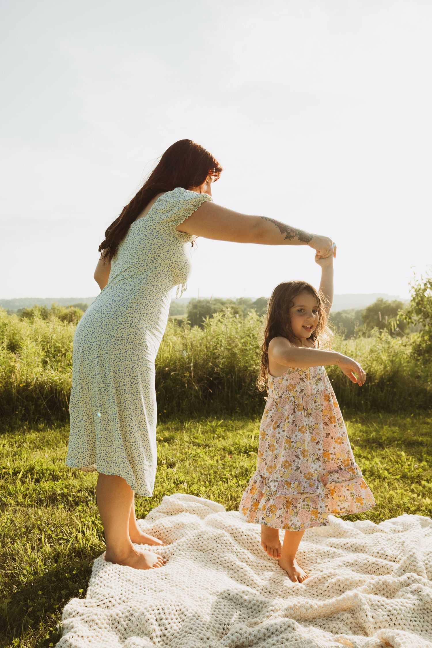 Dancing together on a white blanket in a sun-drenched summer field.