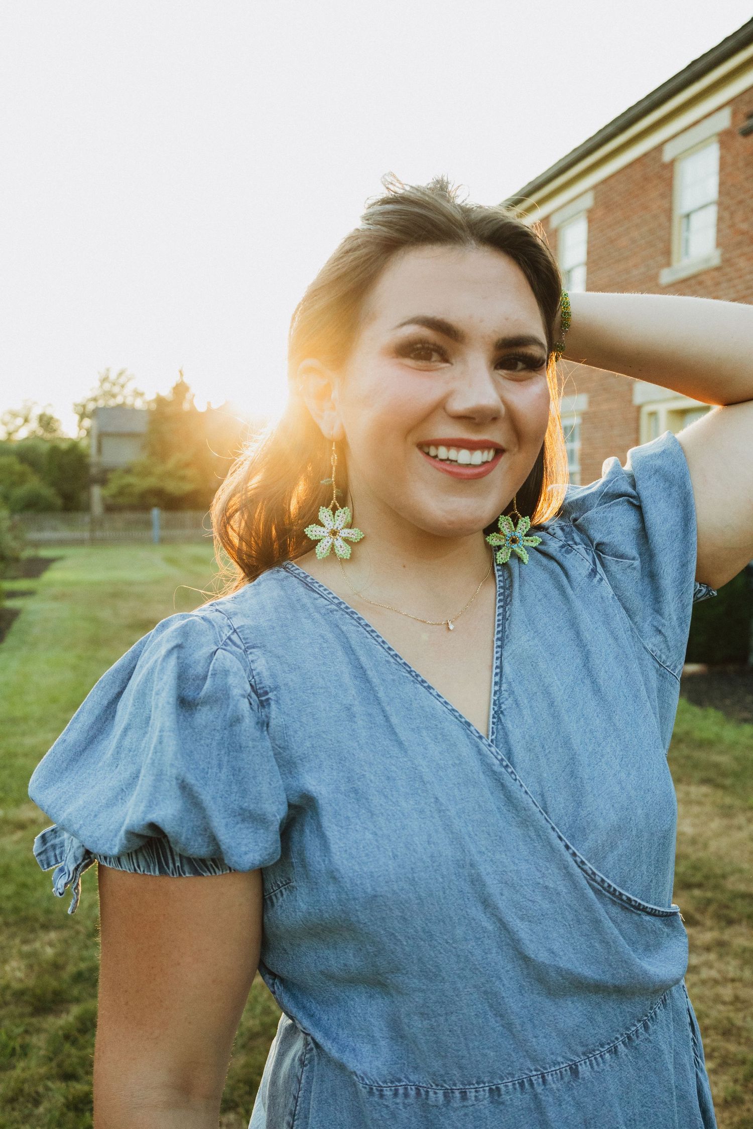 Denim dress with puff sleeves captured in warm evening sunlight against a brick backdrop.