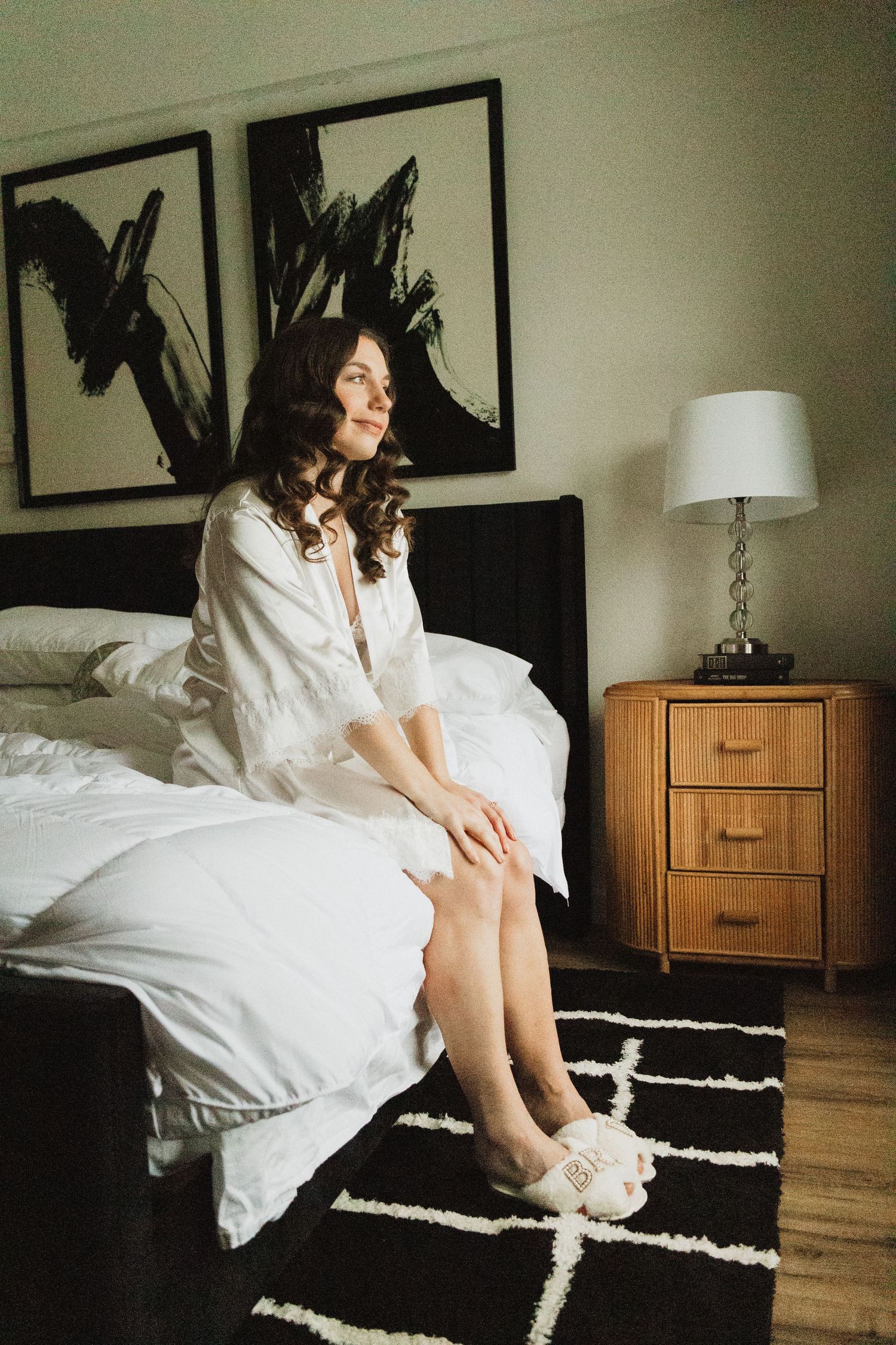 Elegant bedroom setting with black and white art prints, wooden nightstand, and geometric rug.
