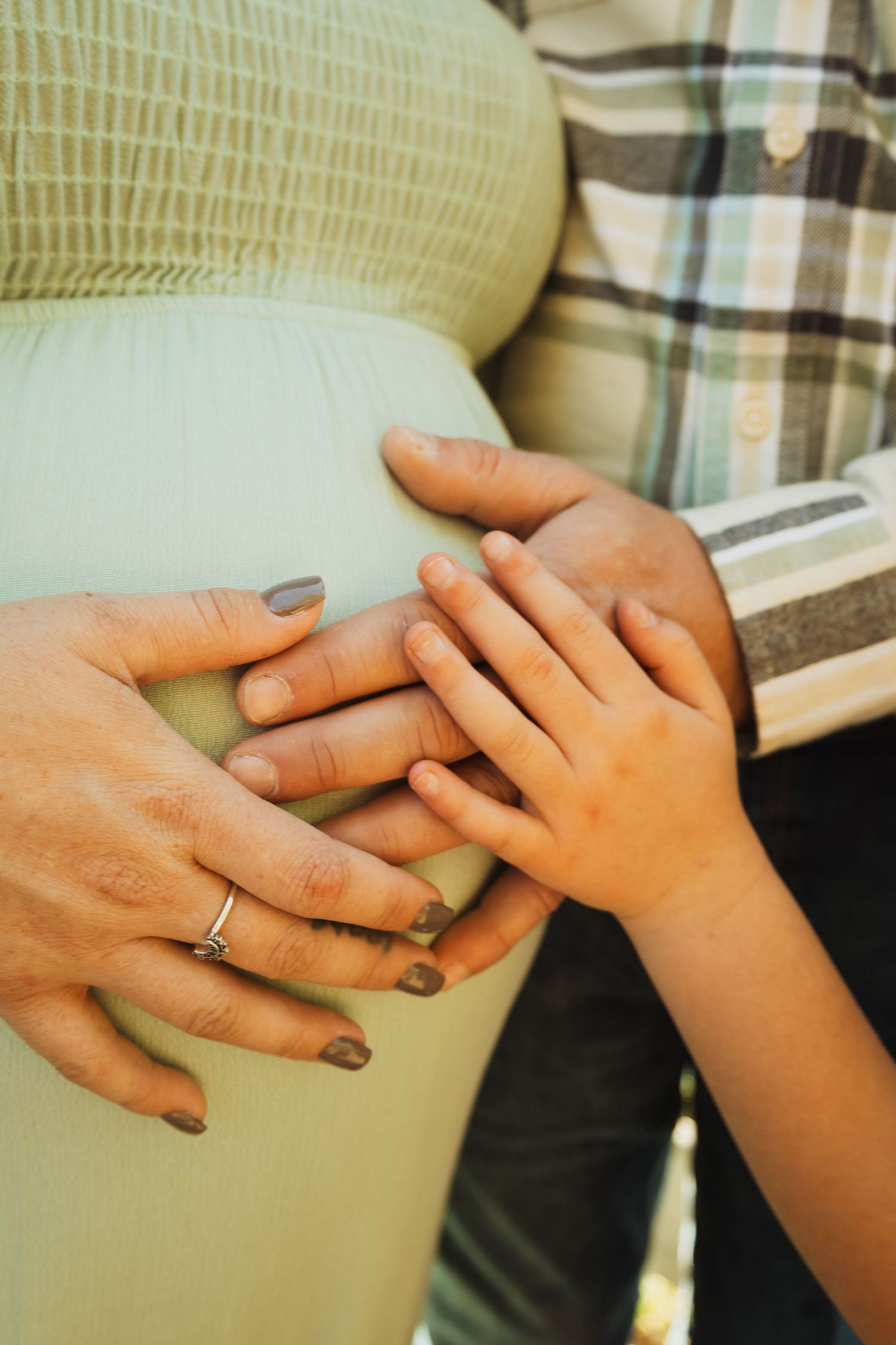 Close-up view of hands with engagement rings intertwined against a plaid background.