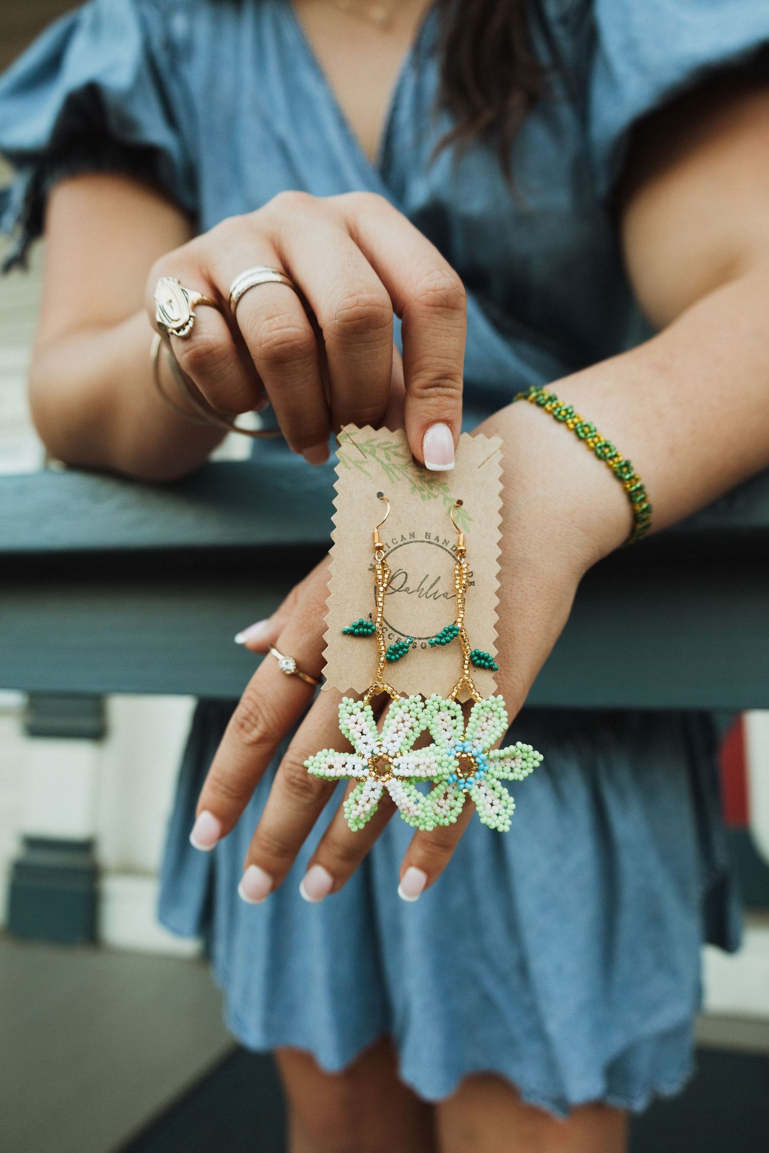 Close-up shots of hands displaying delicate butterfly-themed jewelry pieces against denim fabric.
