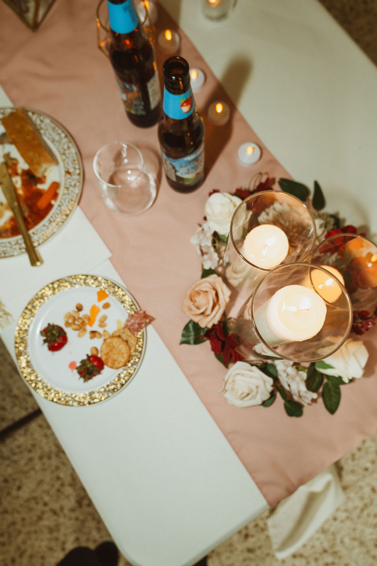 Wedding reception table settings with elegant china plates, candles and floral centerpieces on pink table runners.