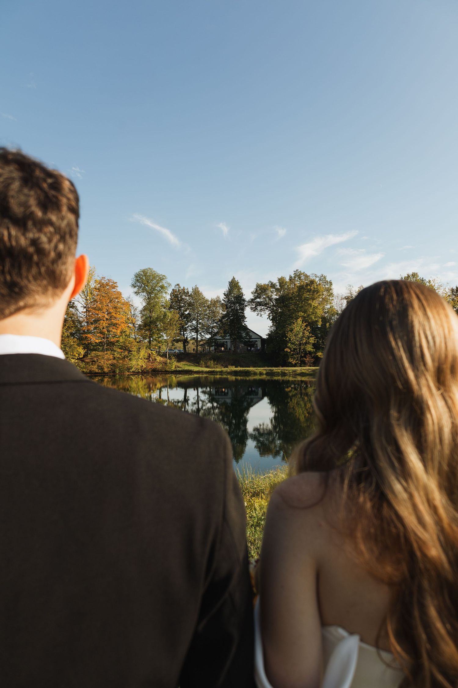 Silhouettes against a serene lake backdrop during golden hour at a wedding.