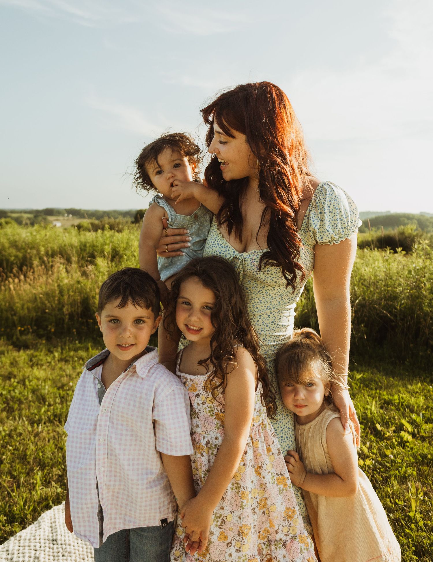 Family gathering on a blanket in a sunlit field sharing joyful moments together.