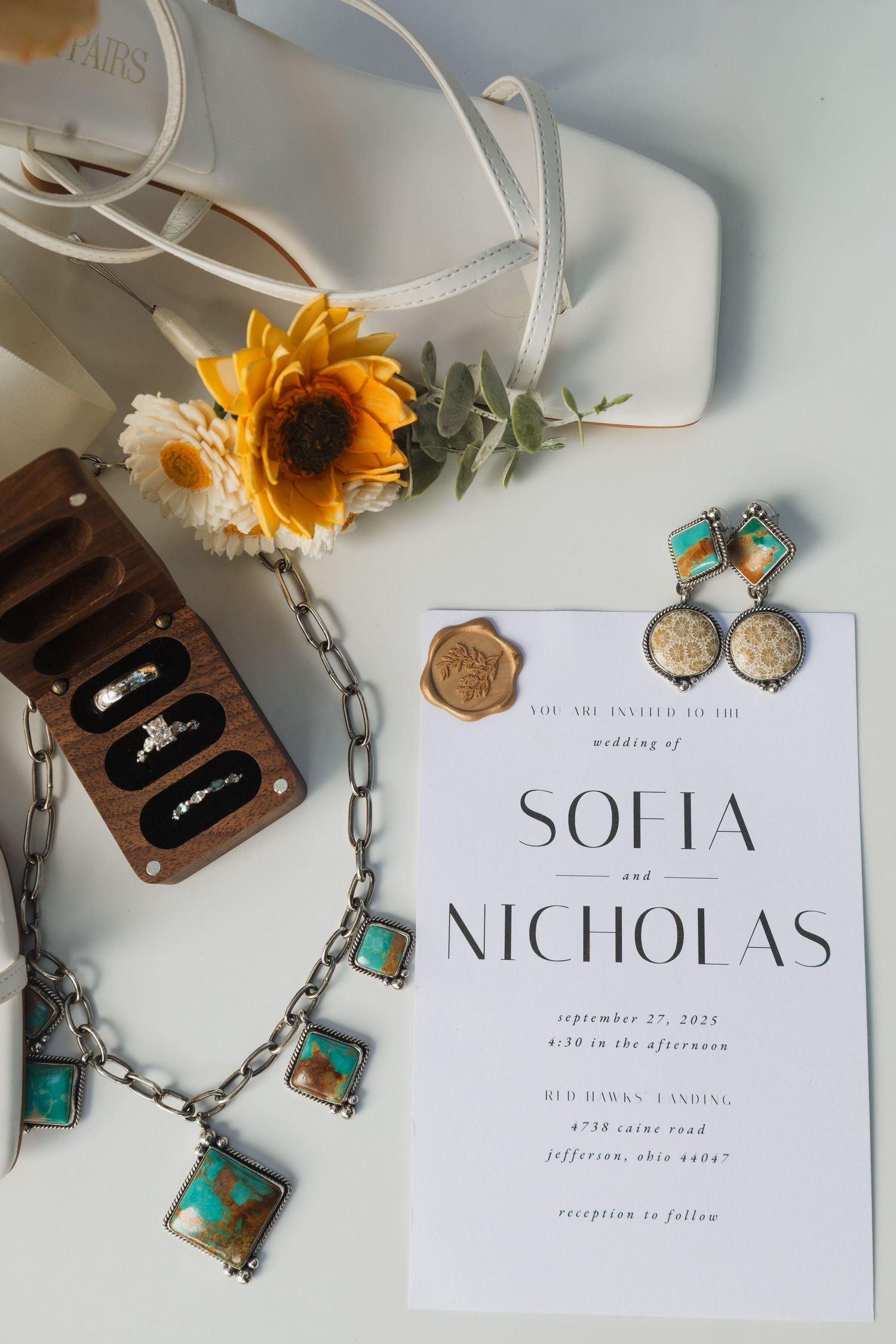 Wedding invitation with Sofia and Nicholas names displayed alongside turquoise jewelry and sunflower accents.