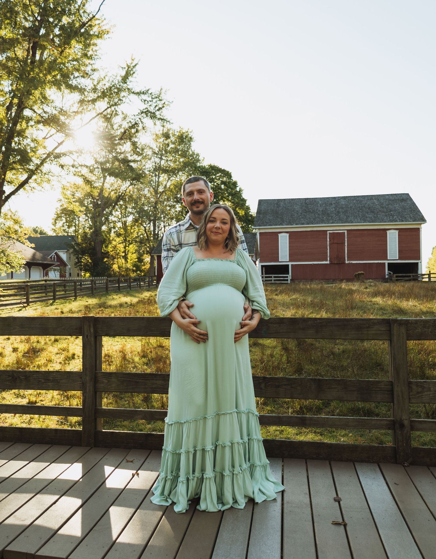 A series of outdoor maternity photos showing a mint green dress against a rustic wooden deck and barn backdrop.