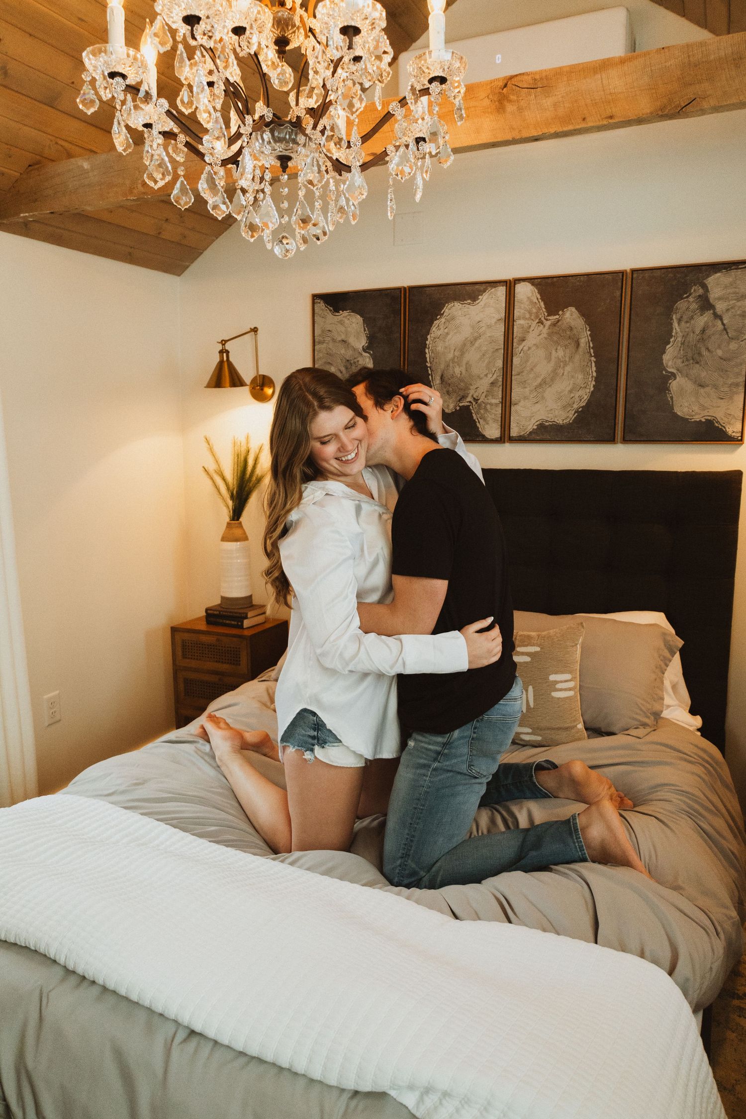 Cozy bedroom interior featuring wood beams, crystal chandelier and abstract wall art.