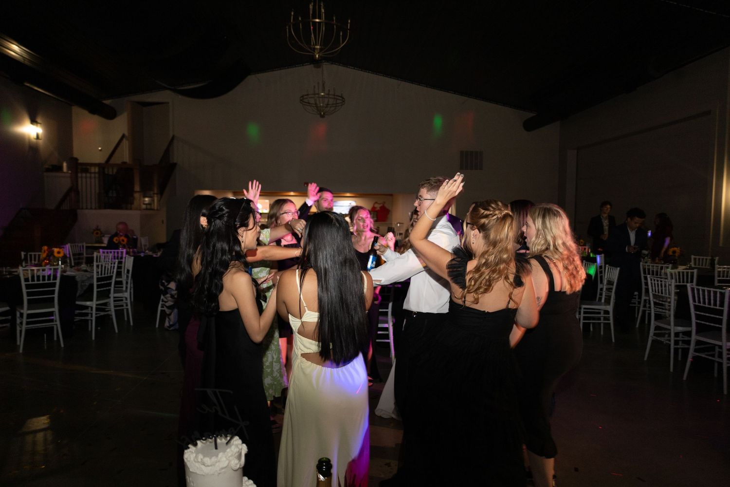 Wedding reception dance floor filled with guests celebrating under warm lighting.