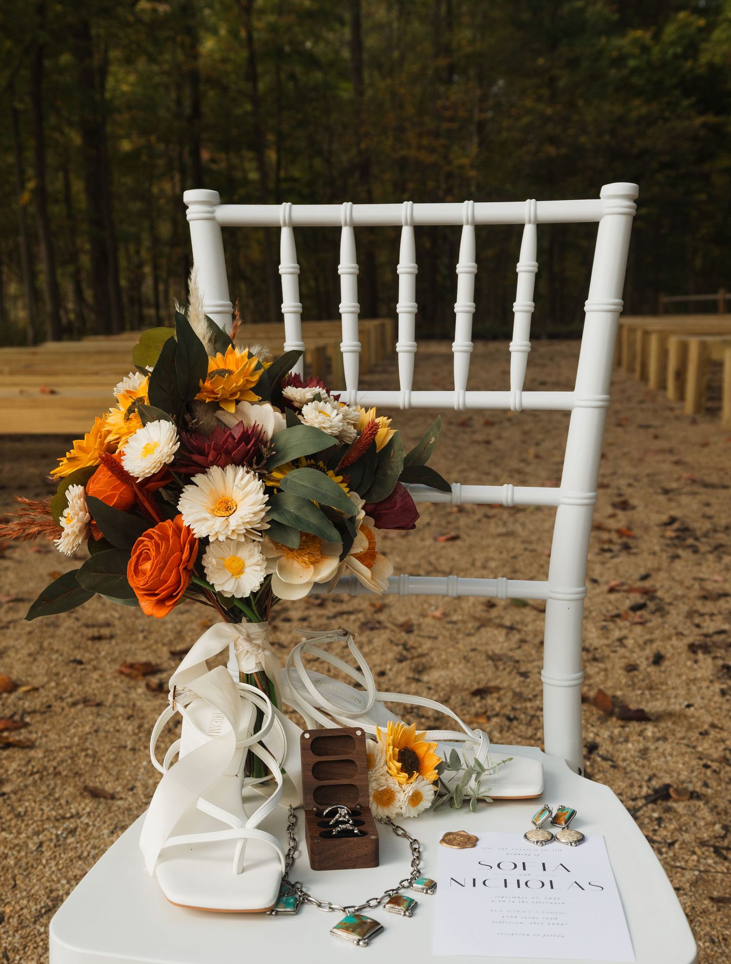 White chiavari chair decorated with fall-colored floral arrangements and wedding details.