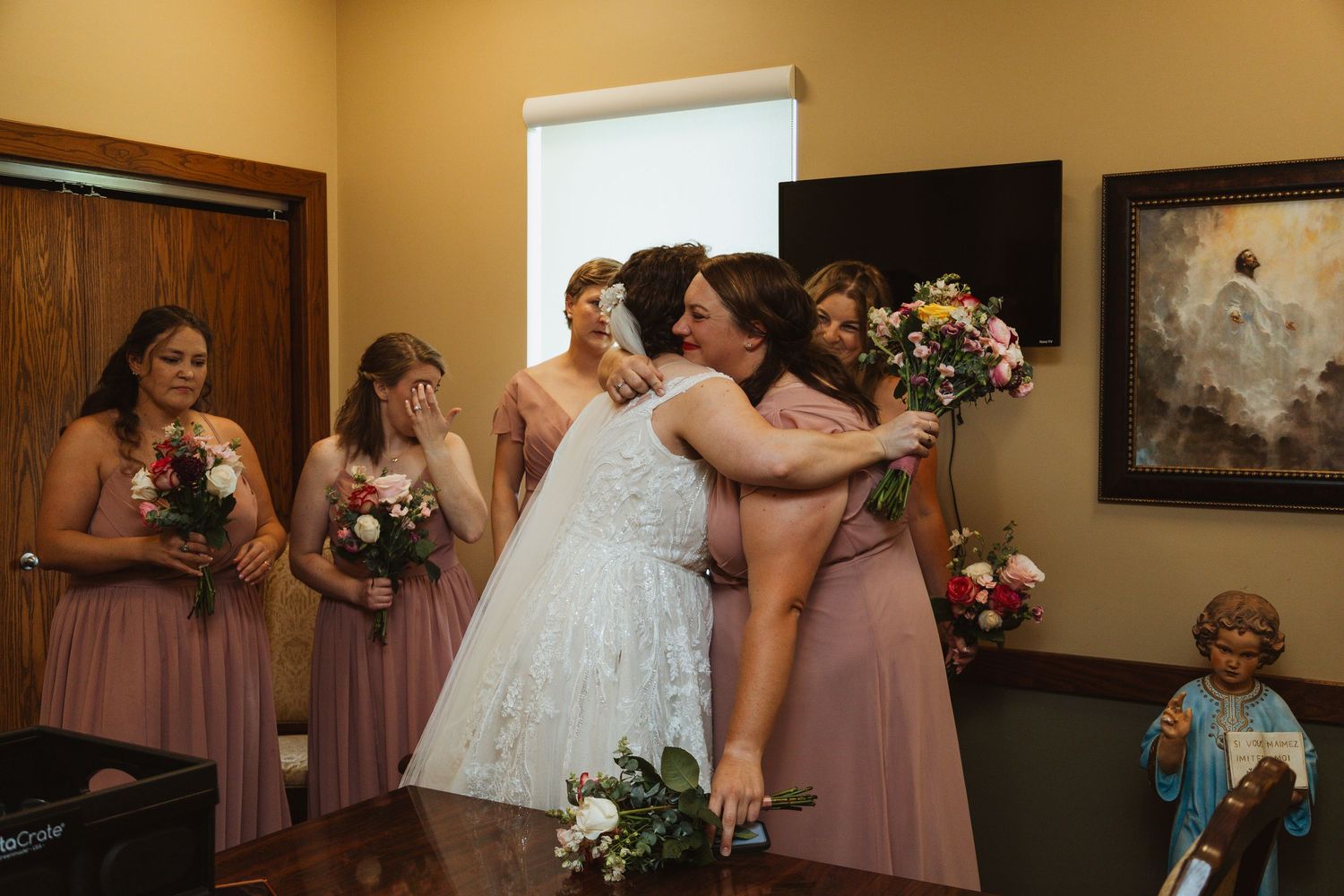 Wedding party members in pink dresses gather during pre-ceremony preparations.