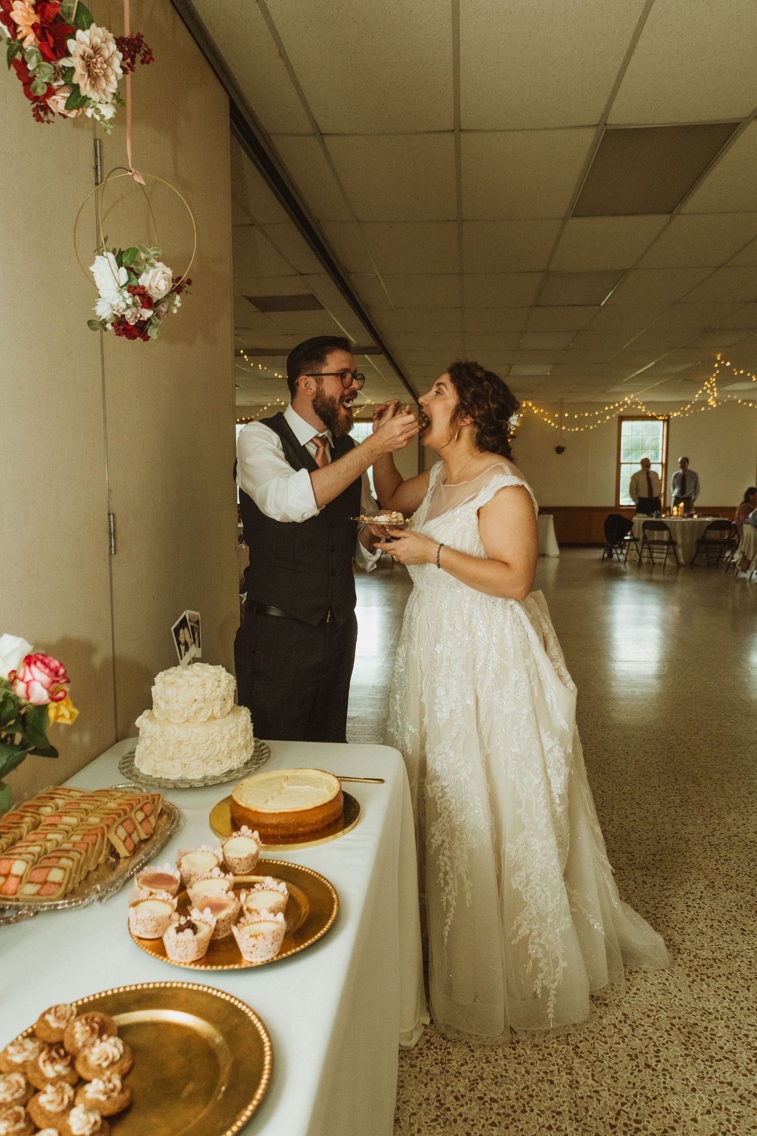 Newlyweds share their first bite of wedding cake together at the reception dessert table.