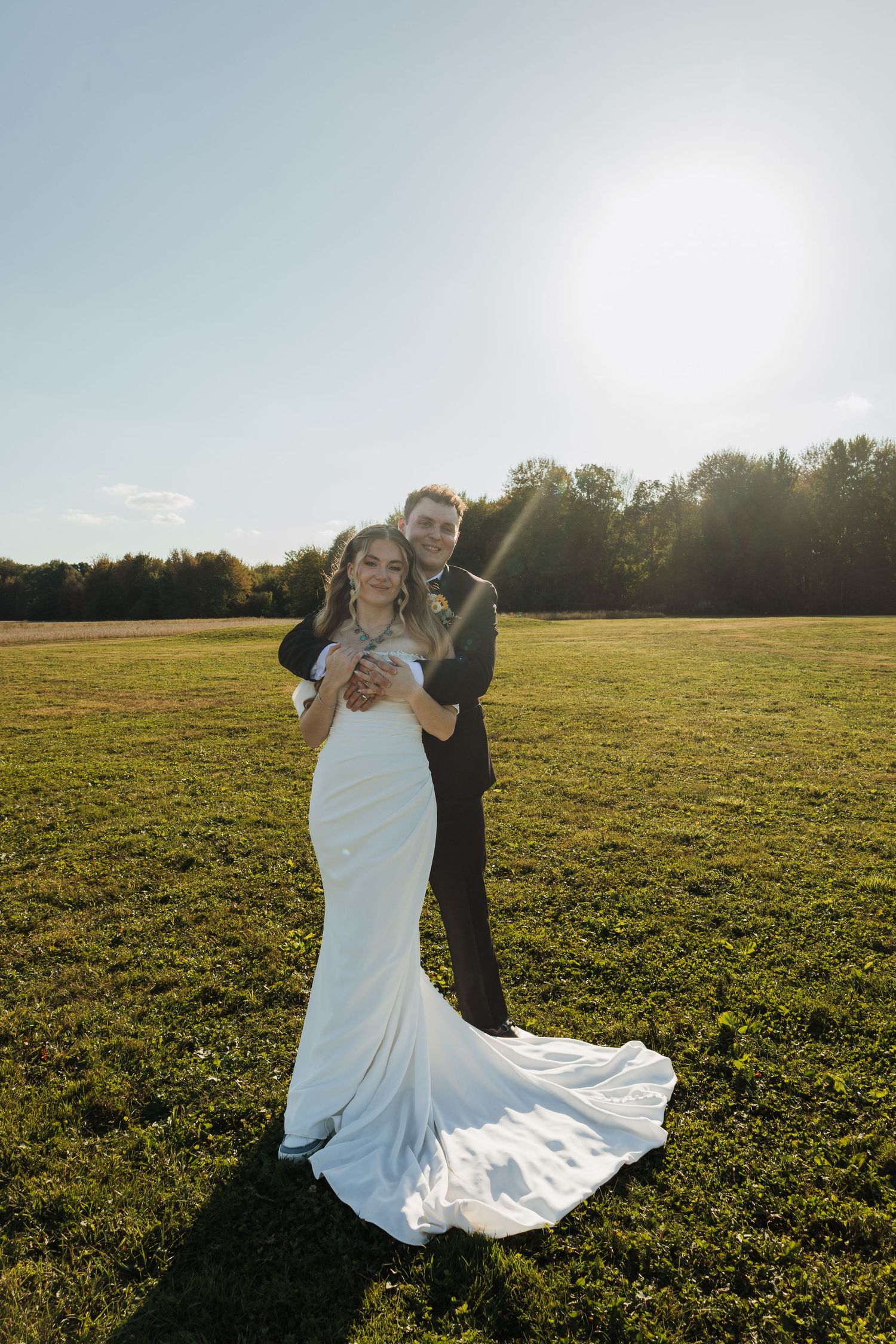 Couple dancing in a golden sunlit field during sunset with the bride's white dress flowing elegantly.