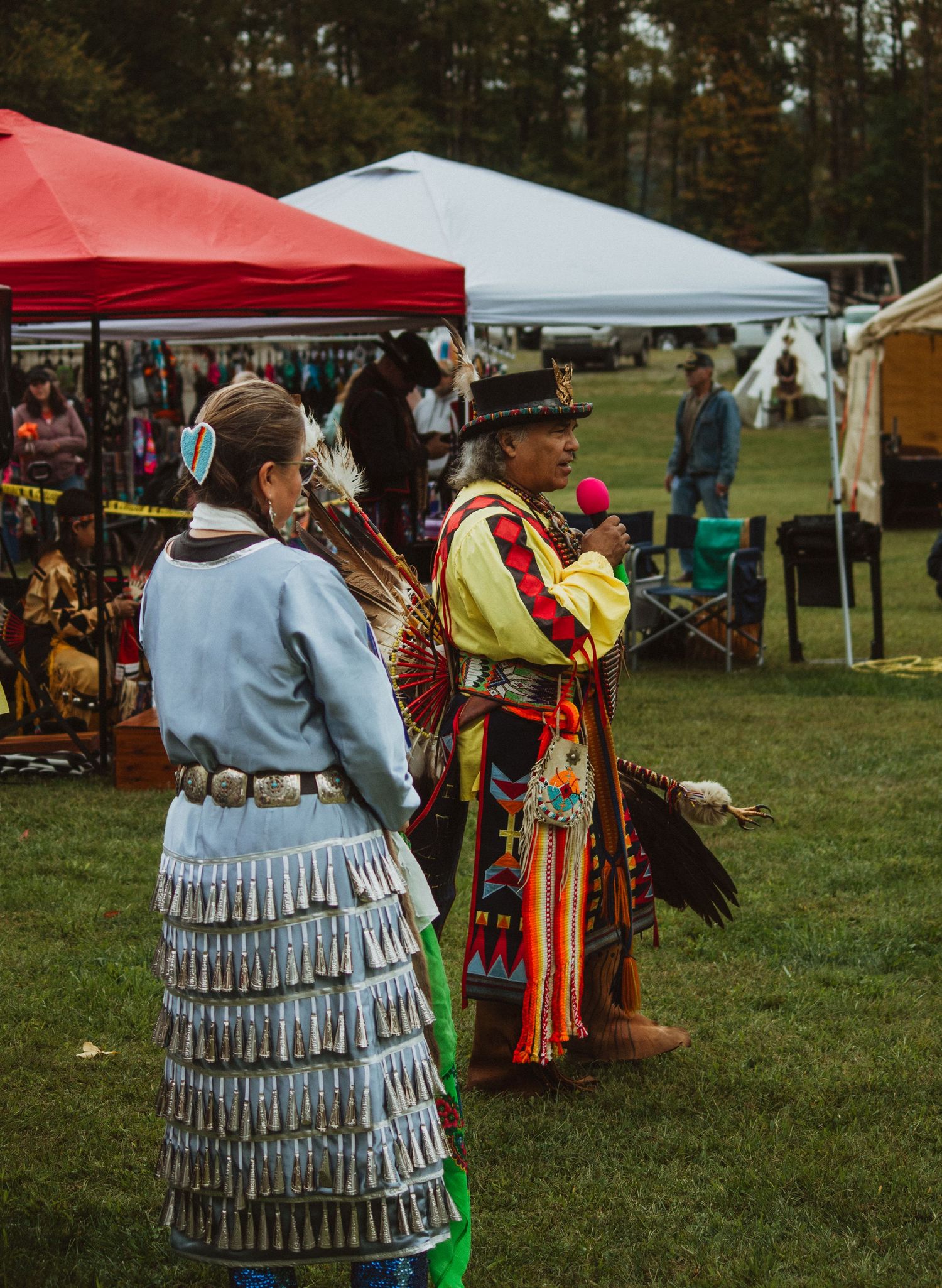 Traditional Native American dancers in ornate regalia perform at an outdoor cultural festival.