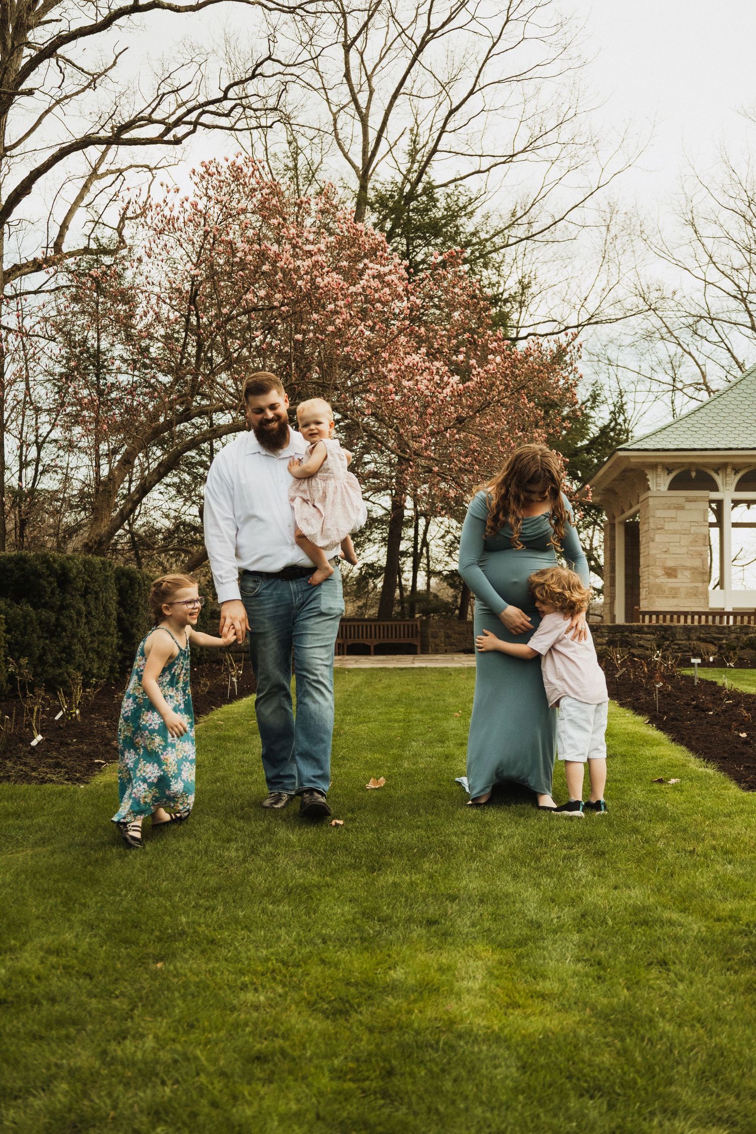 Tender family moment captured under pink blossoms in a spring garden setting.