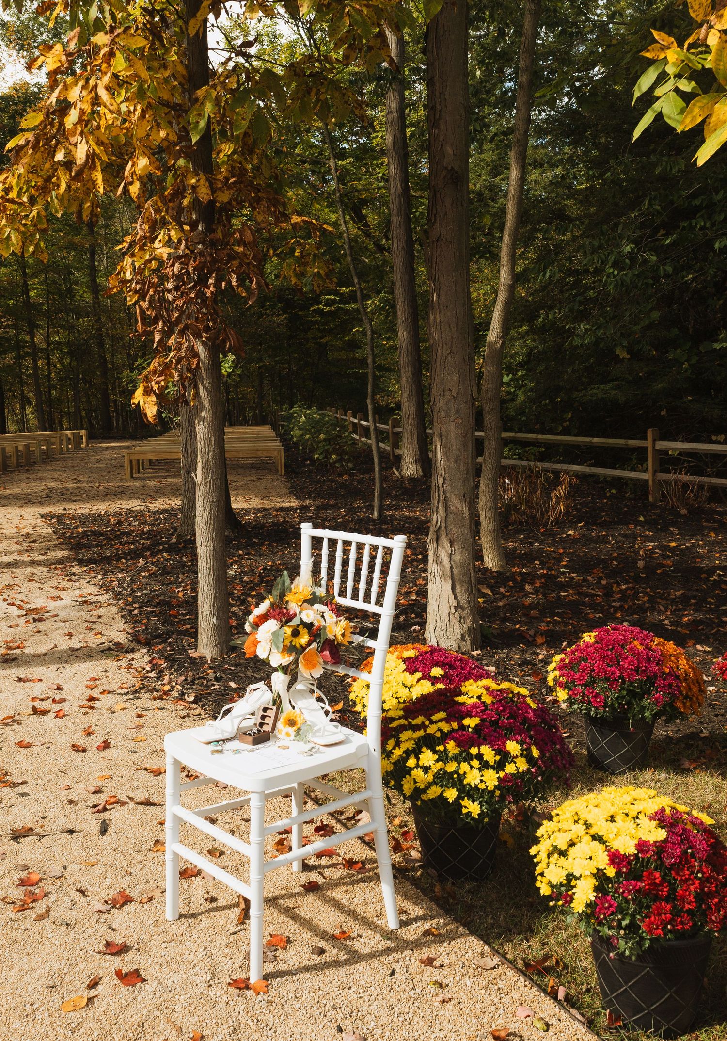 White wooden chair with floral arrangement beside colorful mums on autumn path.