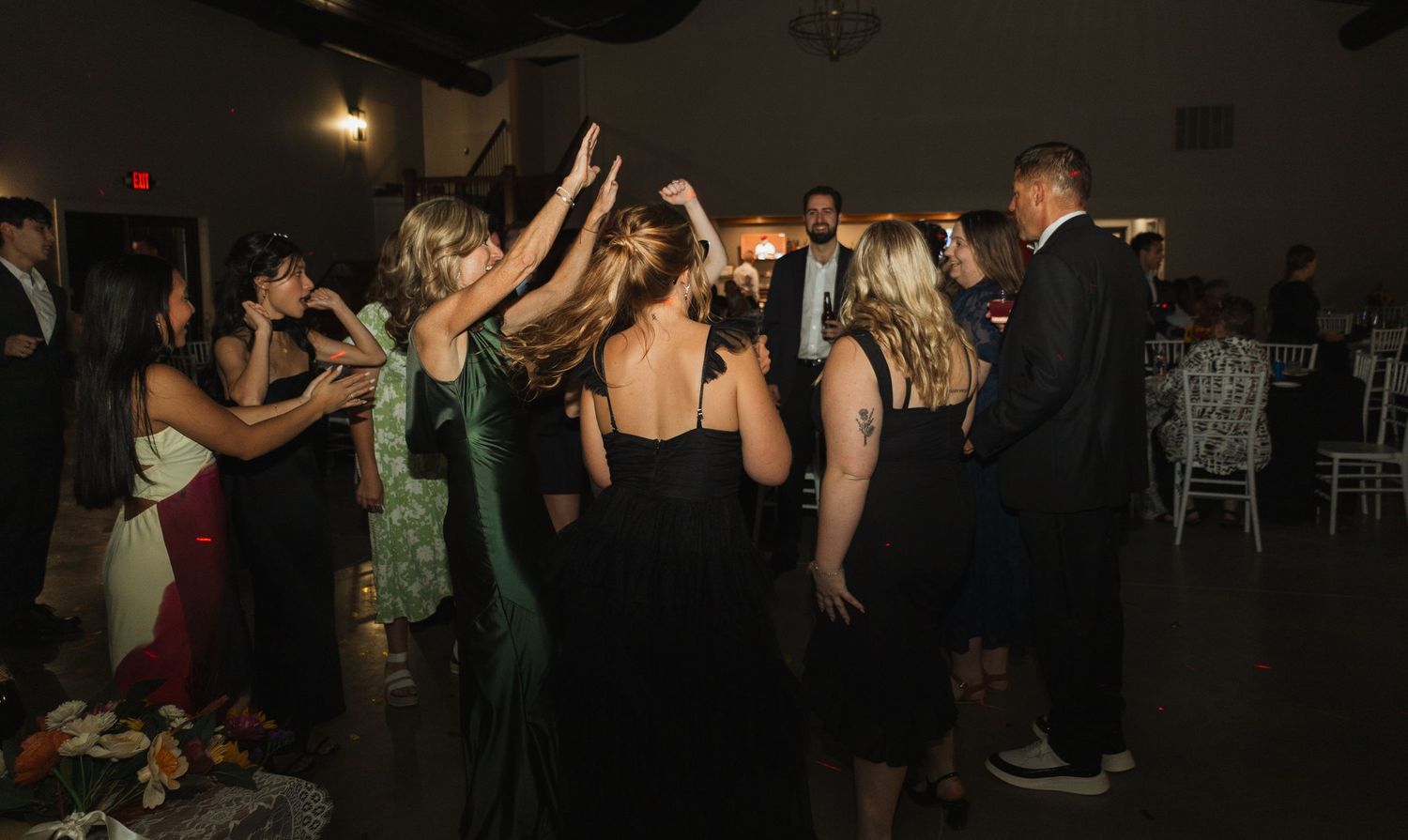Crowded dance floor with party guests enjoying music at evening wedding reception.