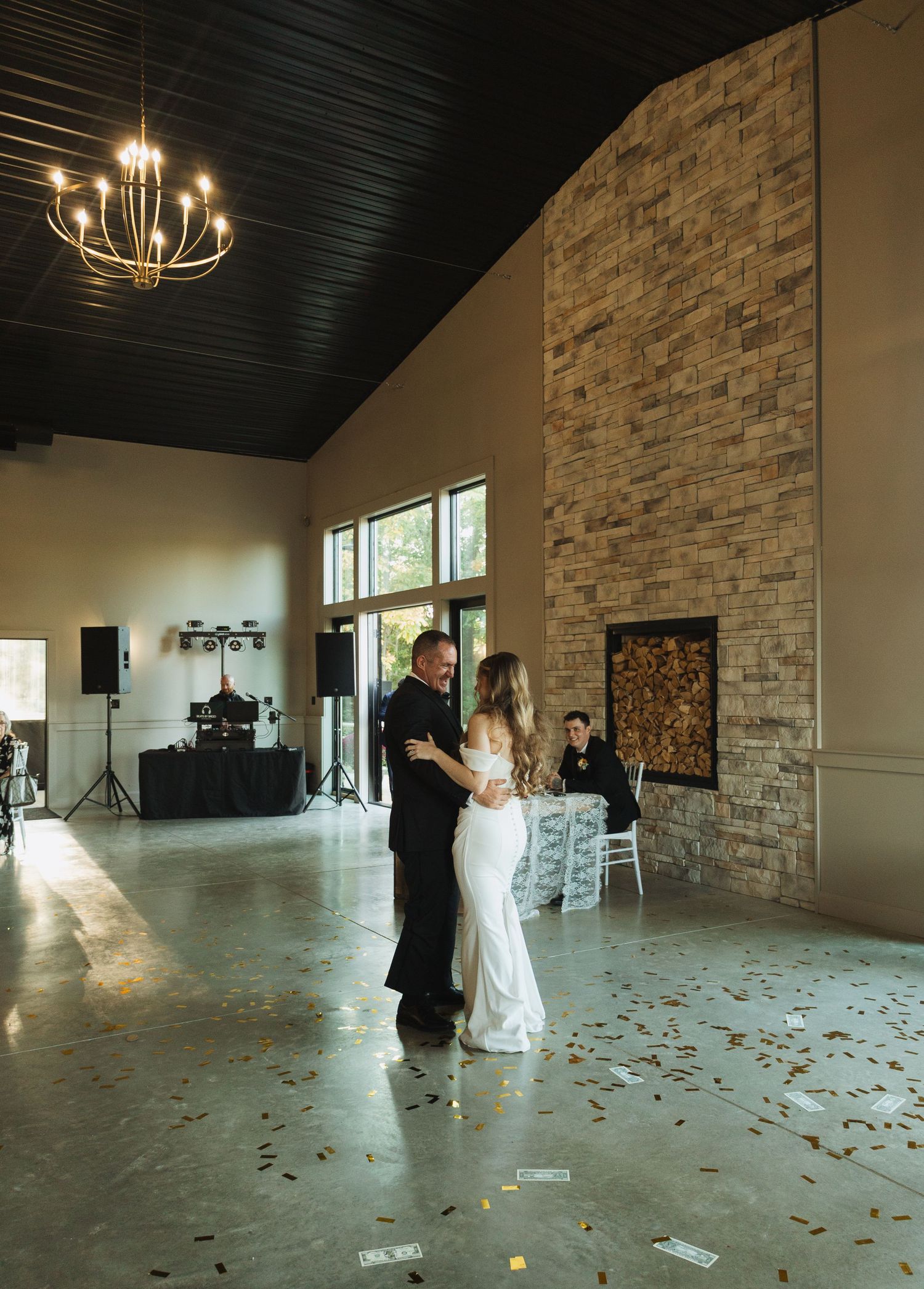 Wedding couple dancing in an elegant venue with stone walls and scattered rose petals on the floor.