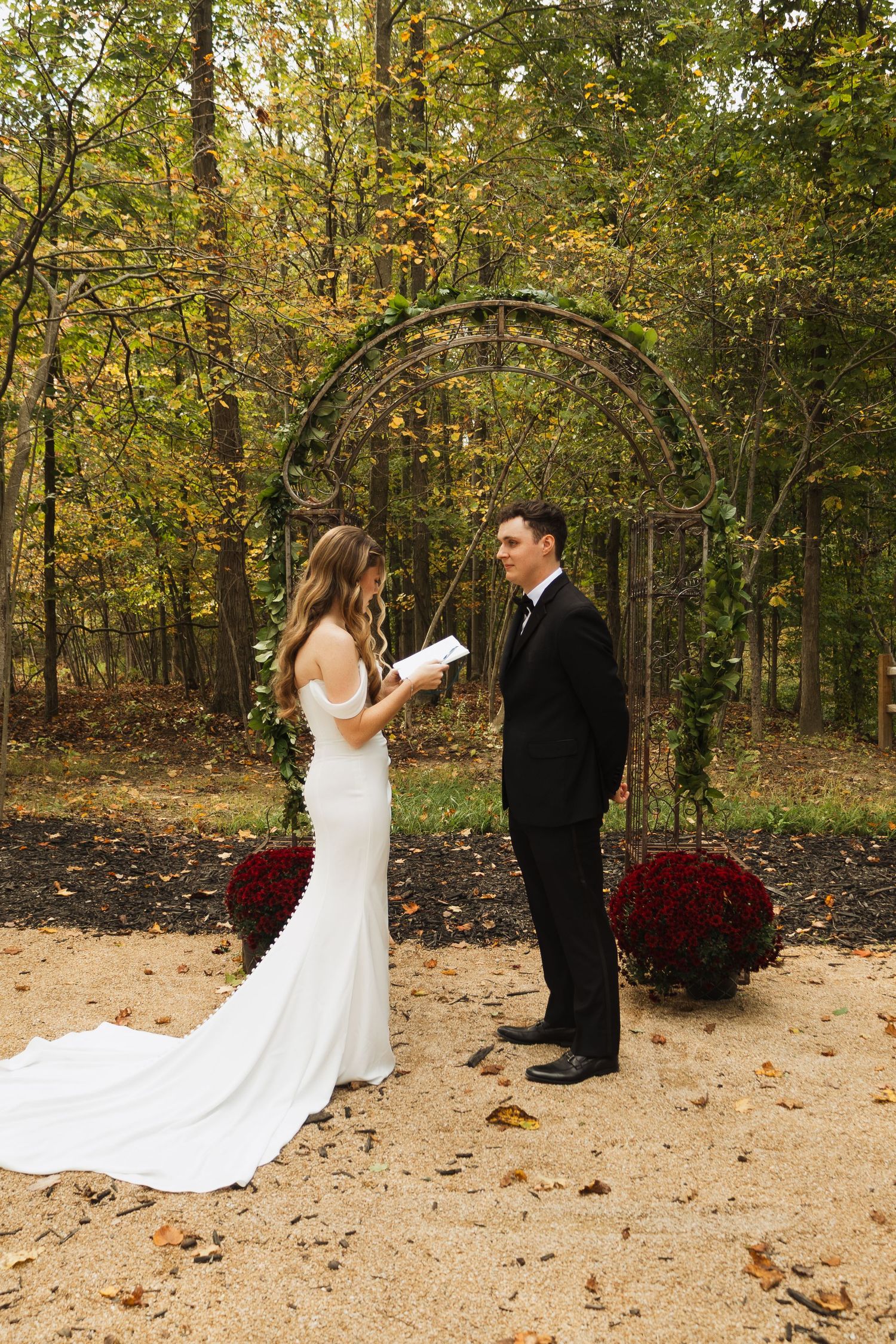 Autumn outdoor wedding first look sequence with fallen leaves and forest backdrop.