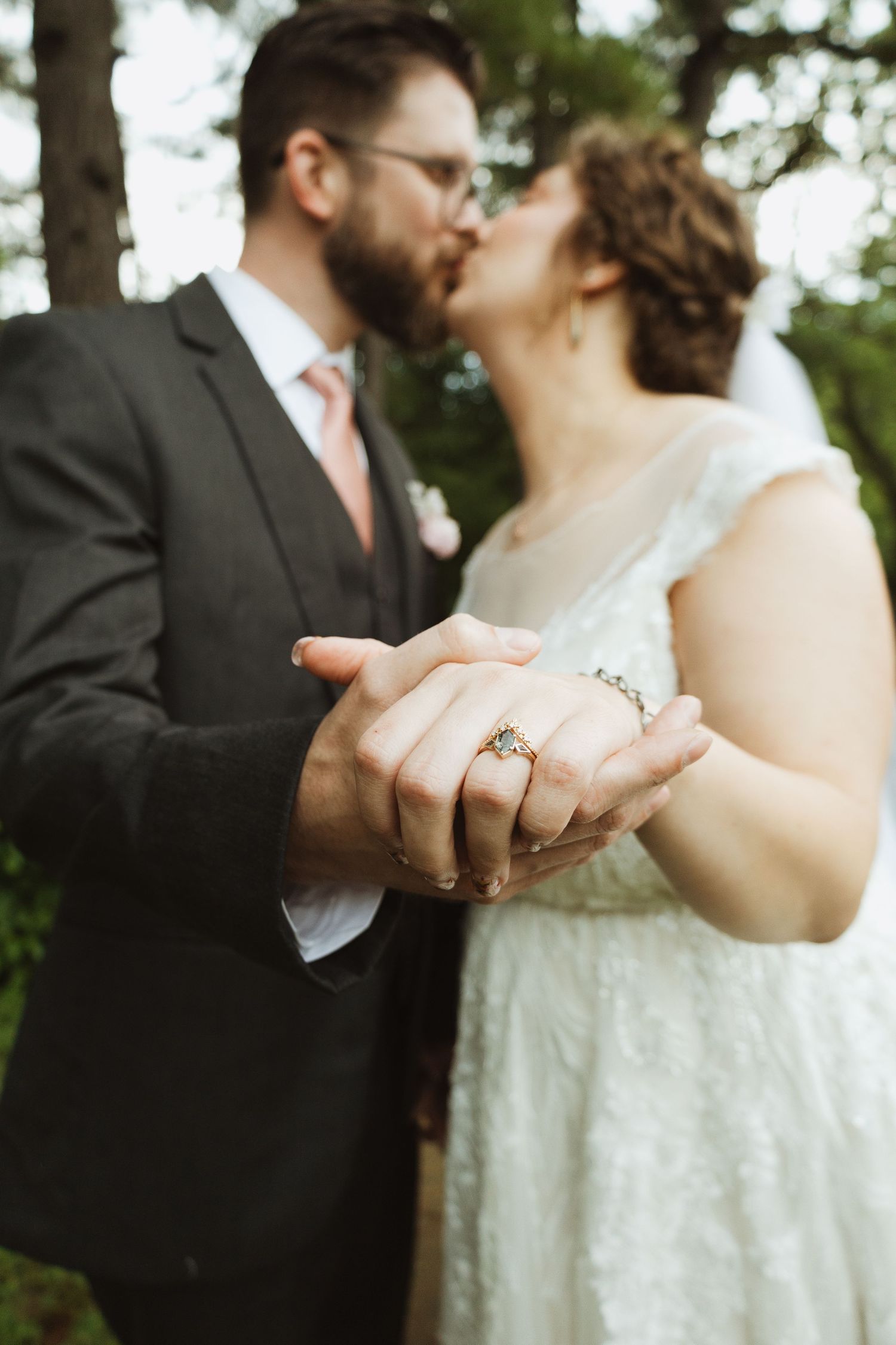 Close-up of newlyweds' hands clasped together while sharing an intimate moment outdoors.