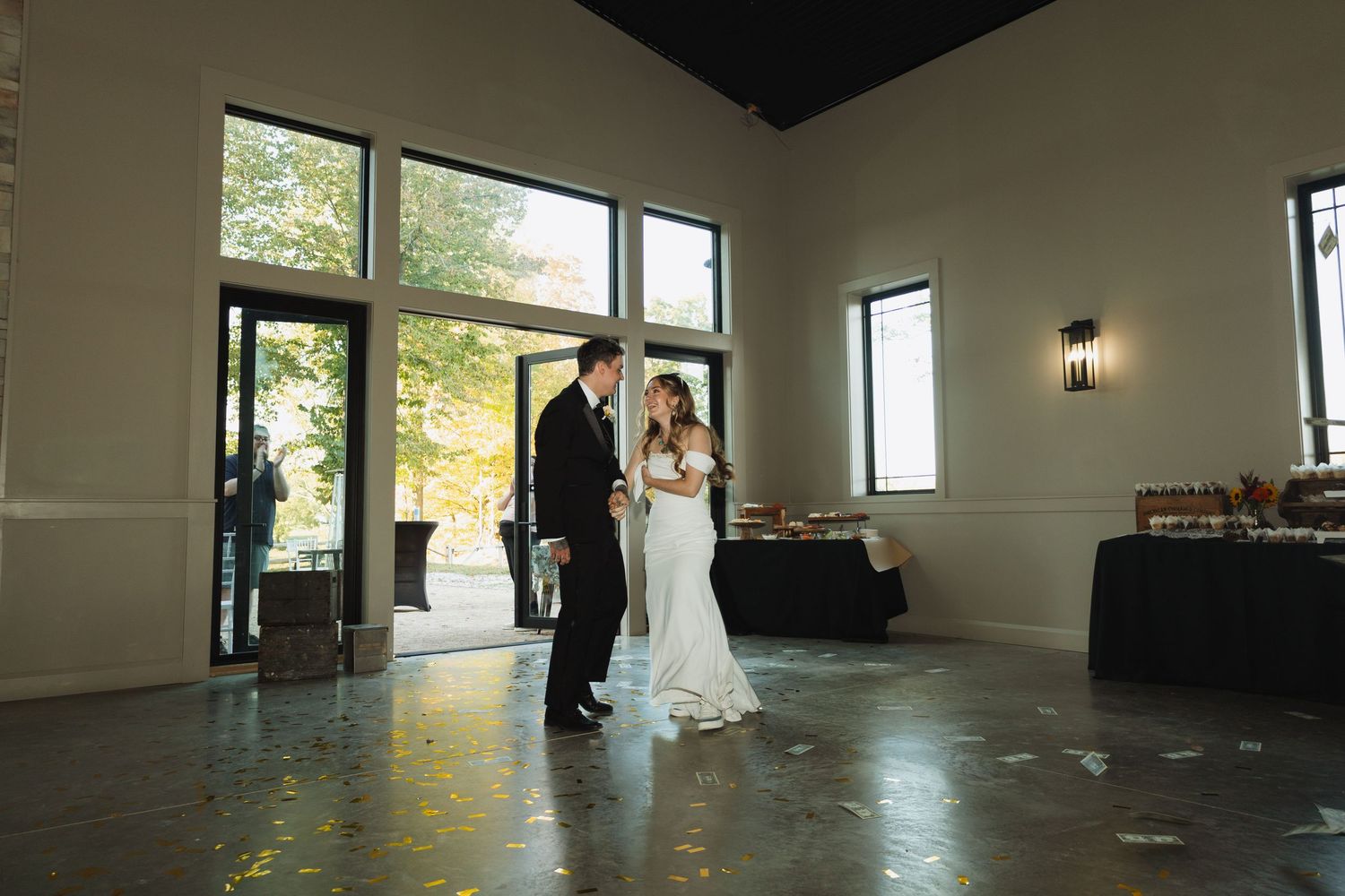 Wedding reception venue setup with elegant black walls and large windows letting in natural light.