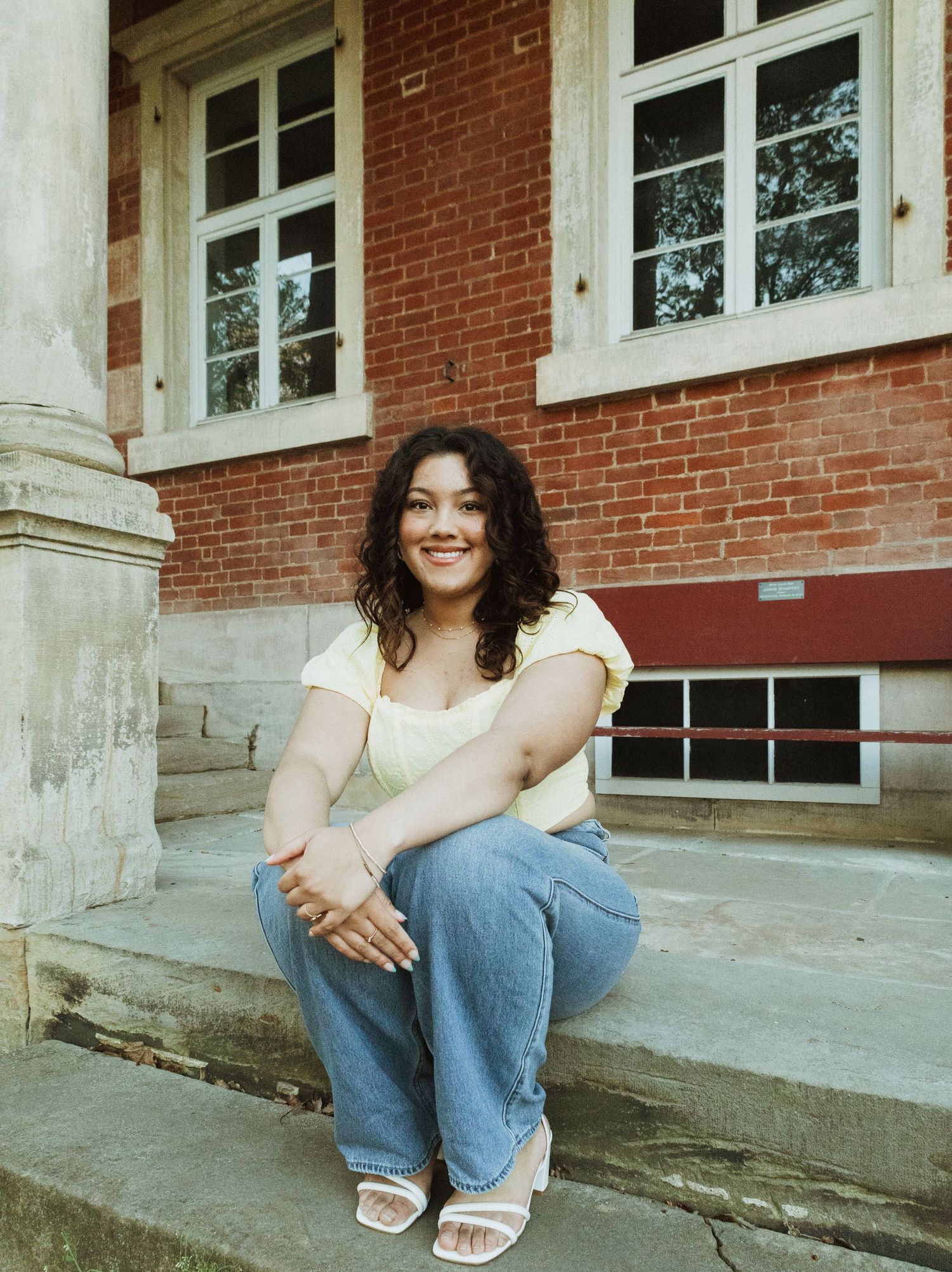 Relaxed portrait on brick building steps with vintage architecture in background.