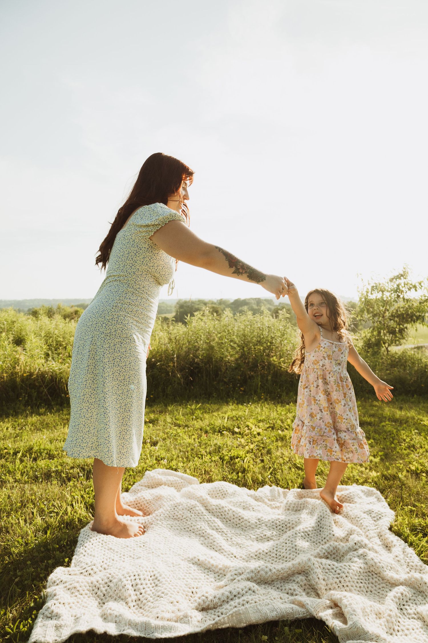 A carefree dance session on a white blanket in a sunny meadow on a summer afternoon.