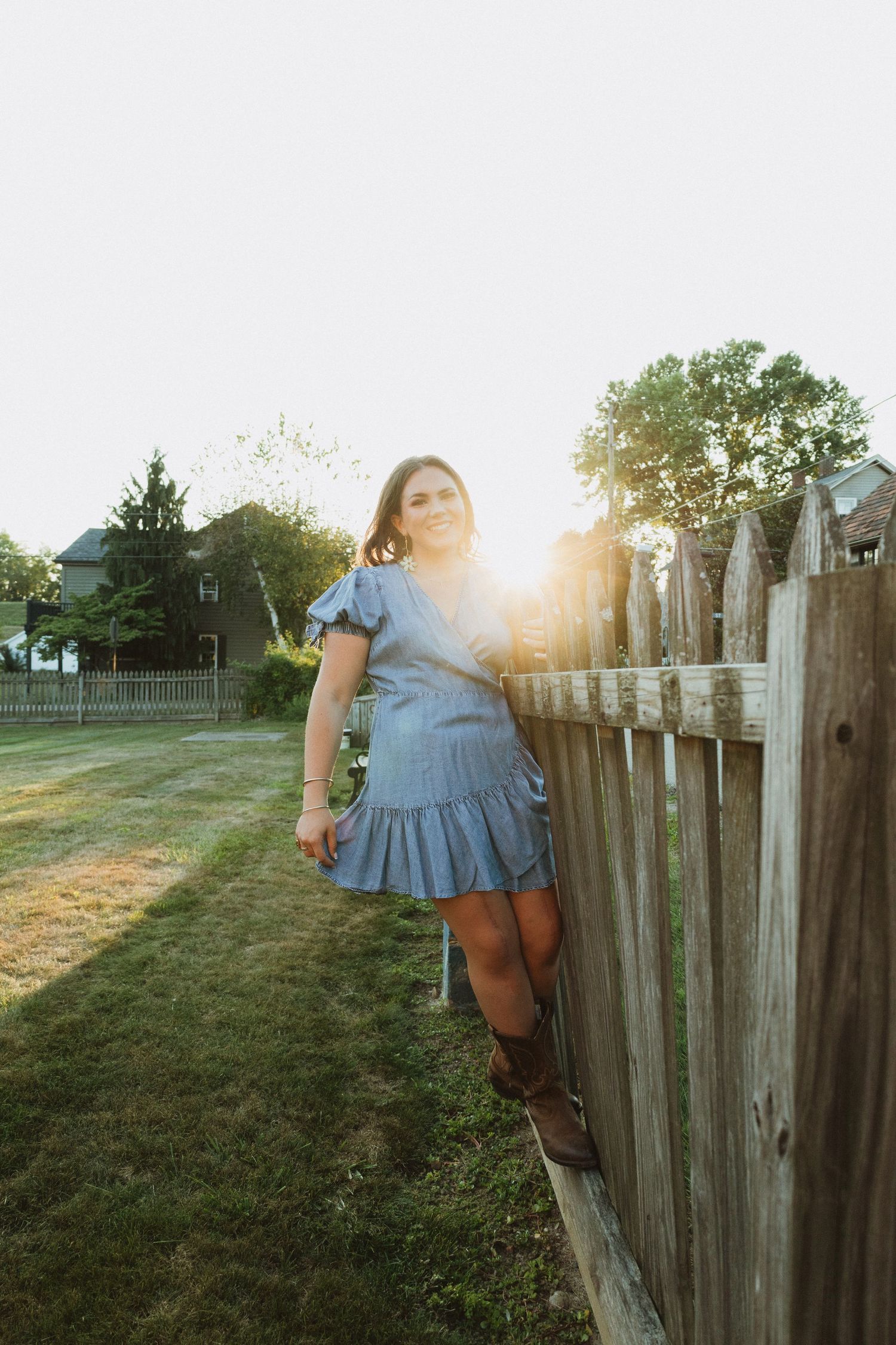 Sunlit golden hour photography session by a rustic wooden fence in a backyard setting.