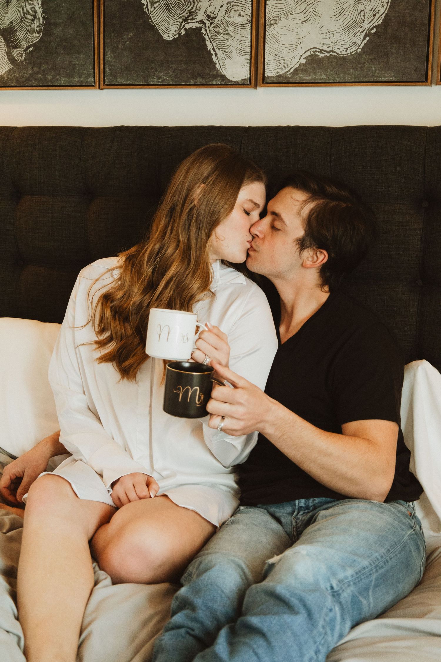 Intimate moment with coffee mugs in modern bedroom featuring abstract wall art and warm lighting.