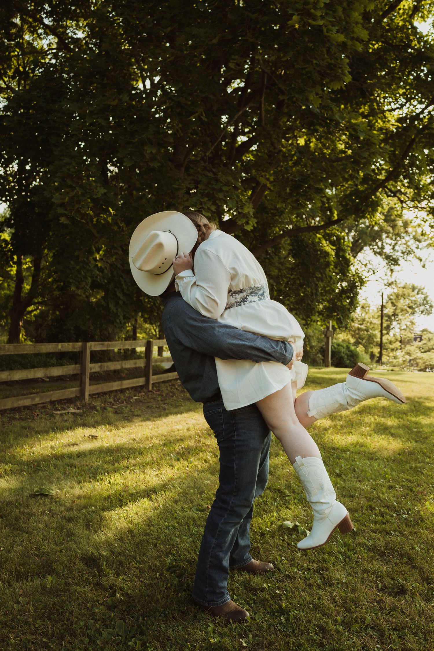 Playful couple dancing and dipping in an outdoor setting with sunlit trees in the background.