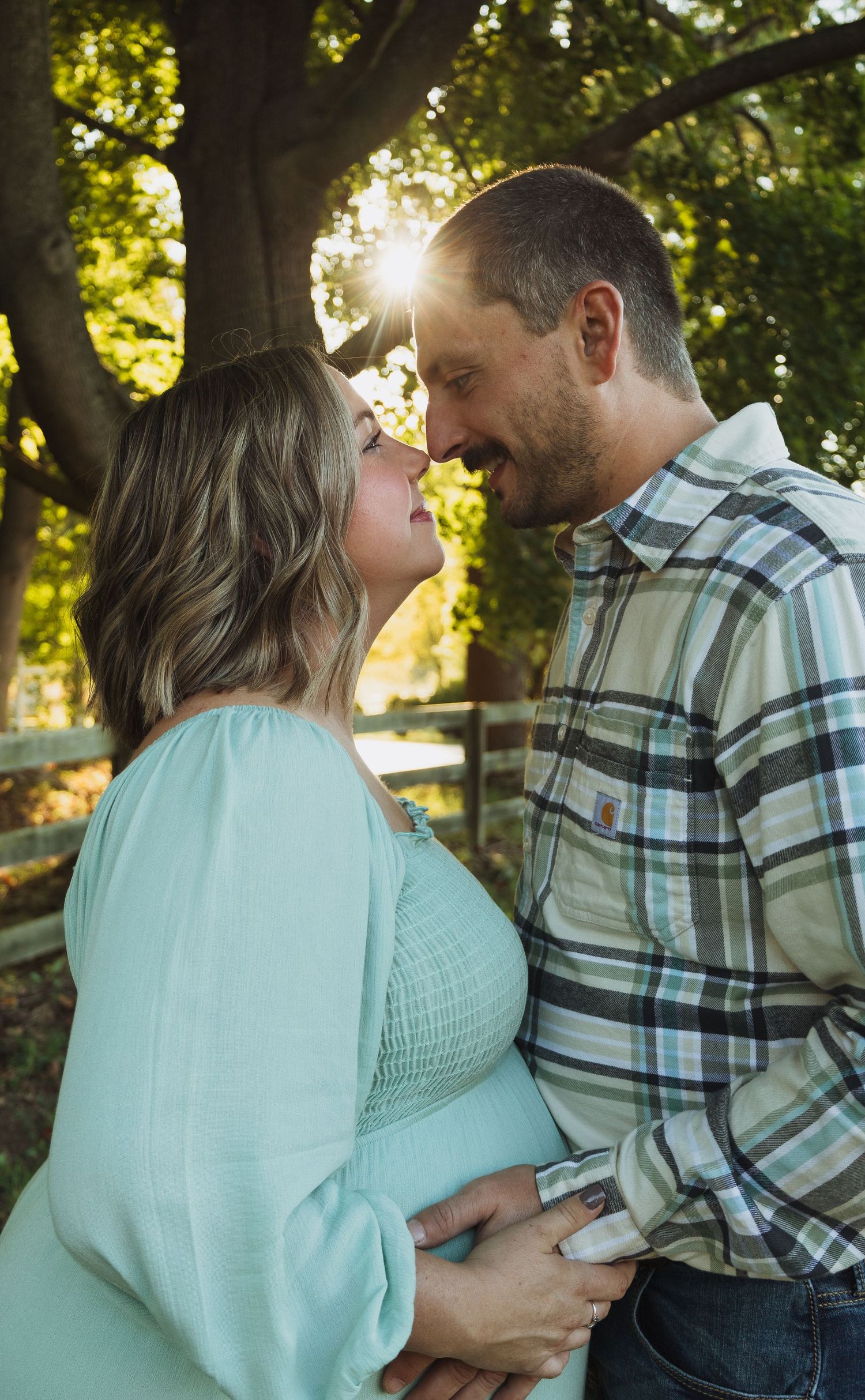Romantic couple in mint green and plaid share tender moments together in a sunlit outdoor setting.