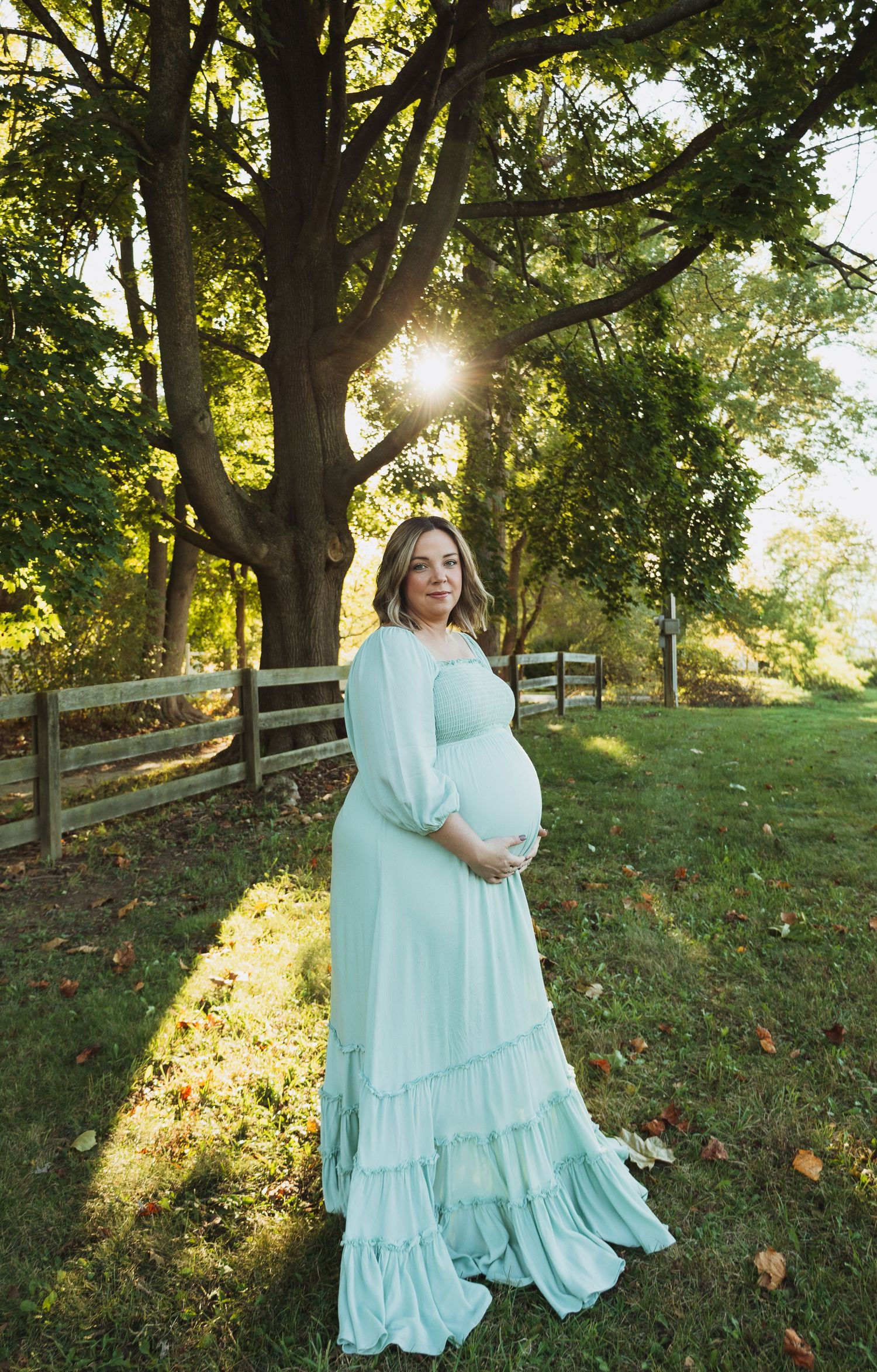A series of outdoor photos showing people in matching light blue flowy dresses standing on a grassy hill at sunset.