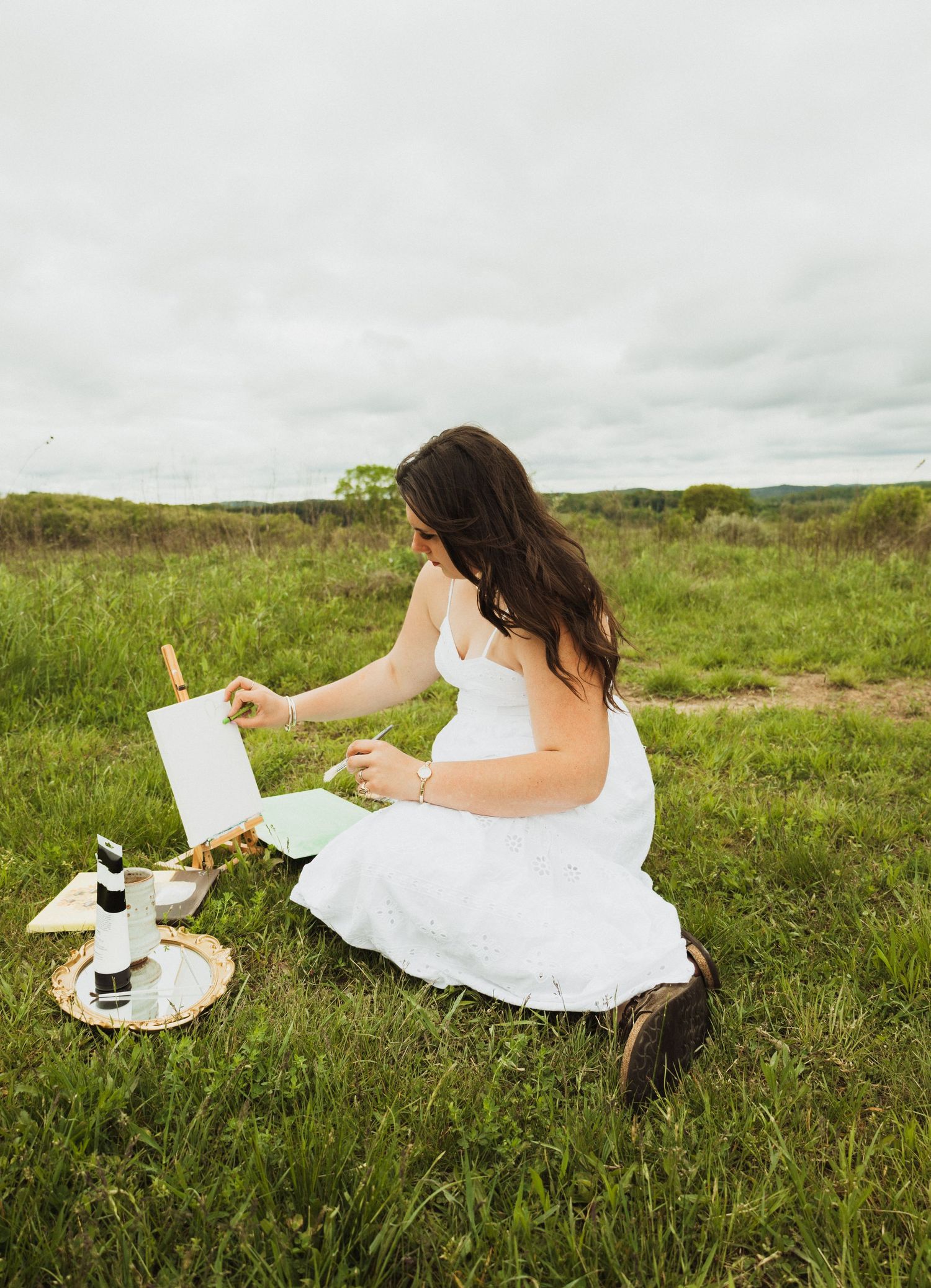 A series of dreamy photos shows someone in a white dress lounging on grass with a journal and picnic setup.