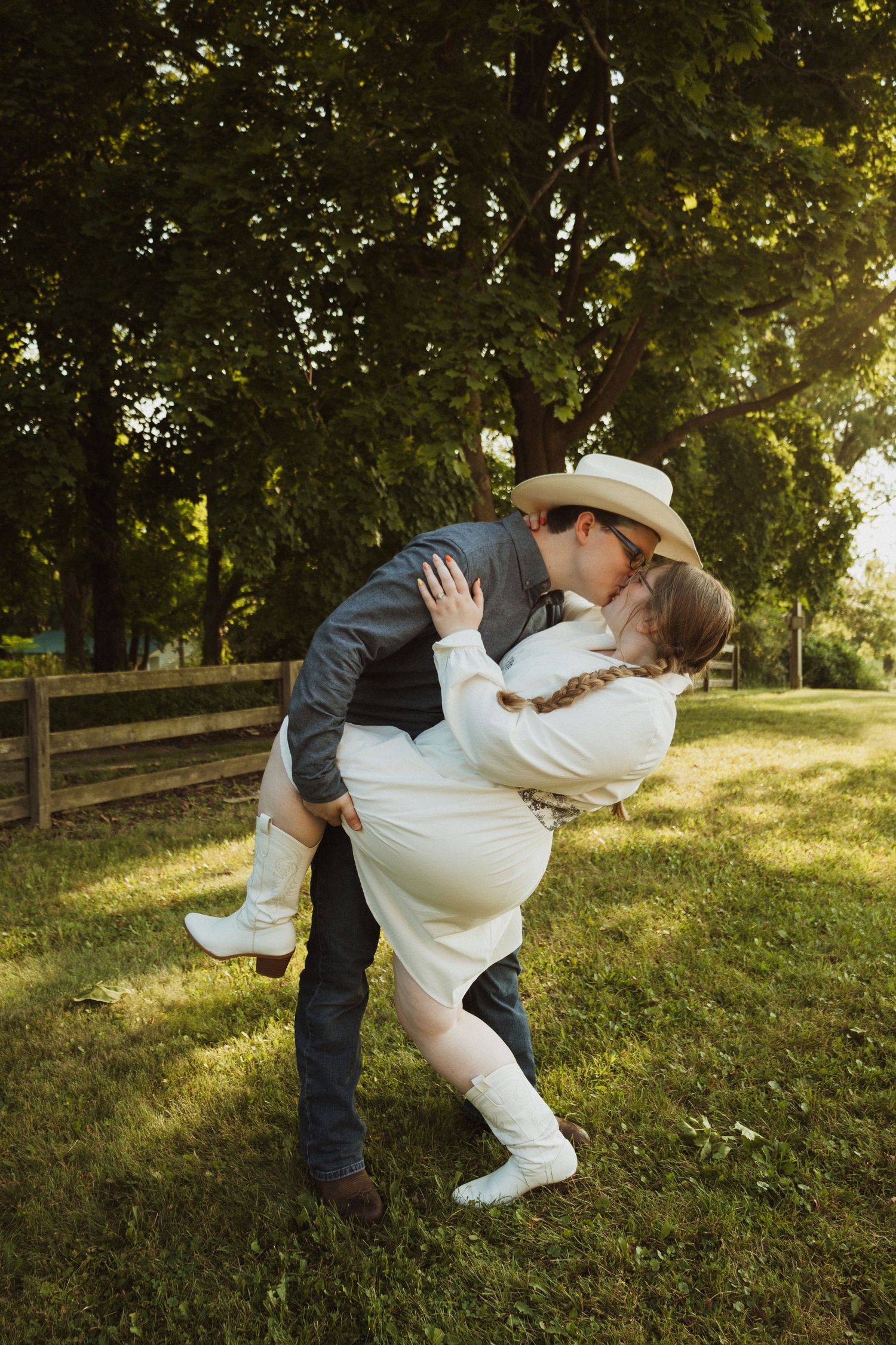 Romantic dip pose during outdoor photoshoot with rustic farm scenery in background.