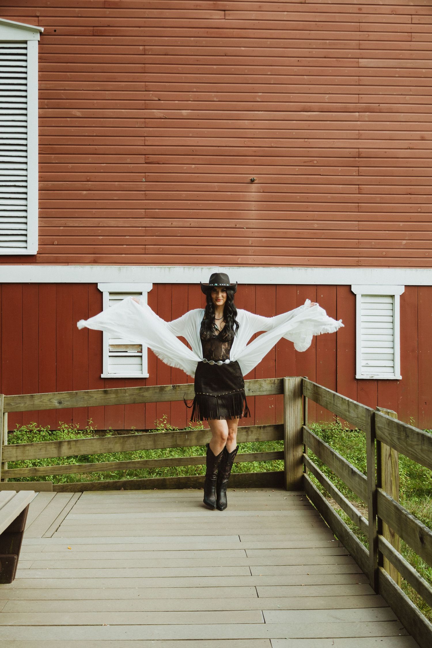 A sequence showing someone spinning and twirling in a white dress against a red barn wall and wooden walkway.
