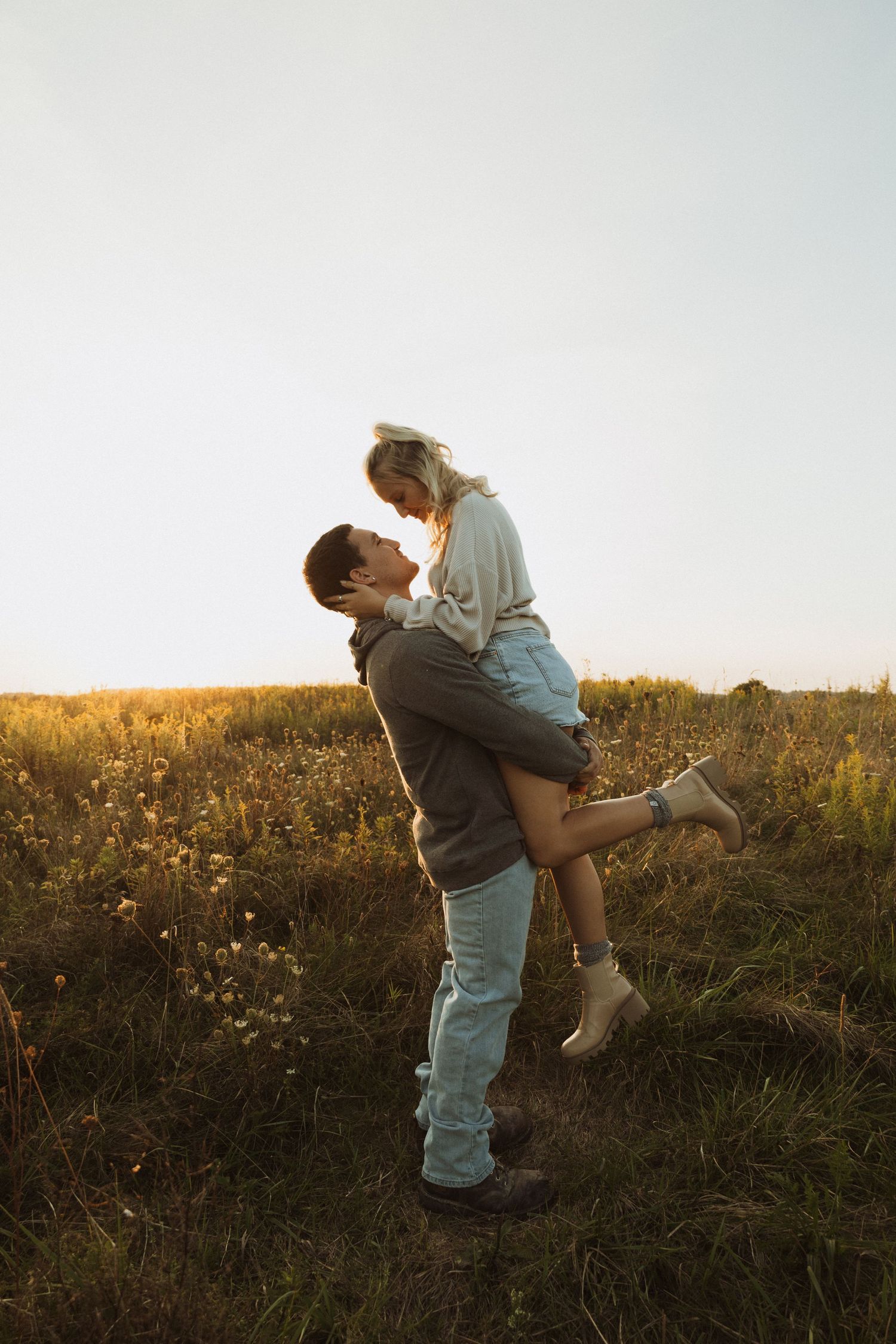 Playful couple moment captured in golden field during sunset.
