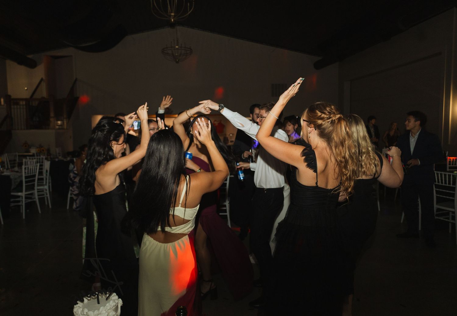 Wedding guests dancing and celebrating on a dimly lit dance floor during the reception.