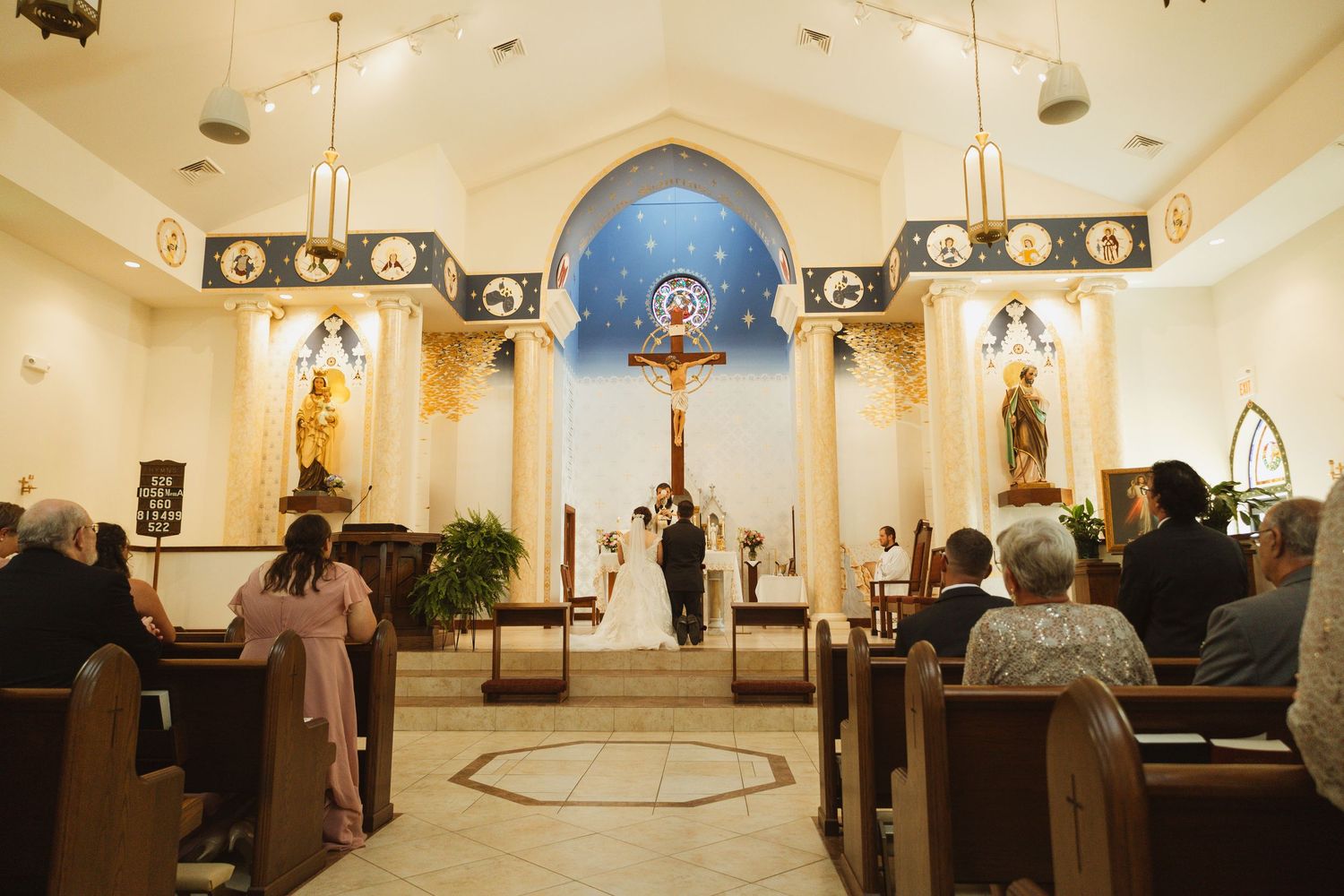 A panoramic view of a wedding ceremony in a church with dramatic lighting and vaulted ceilings.